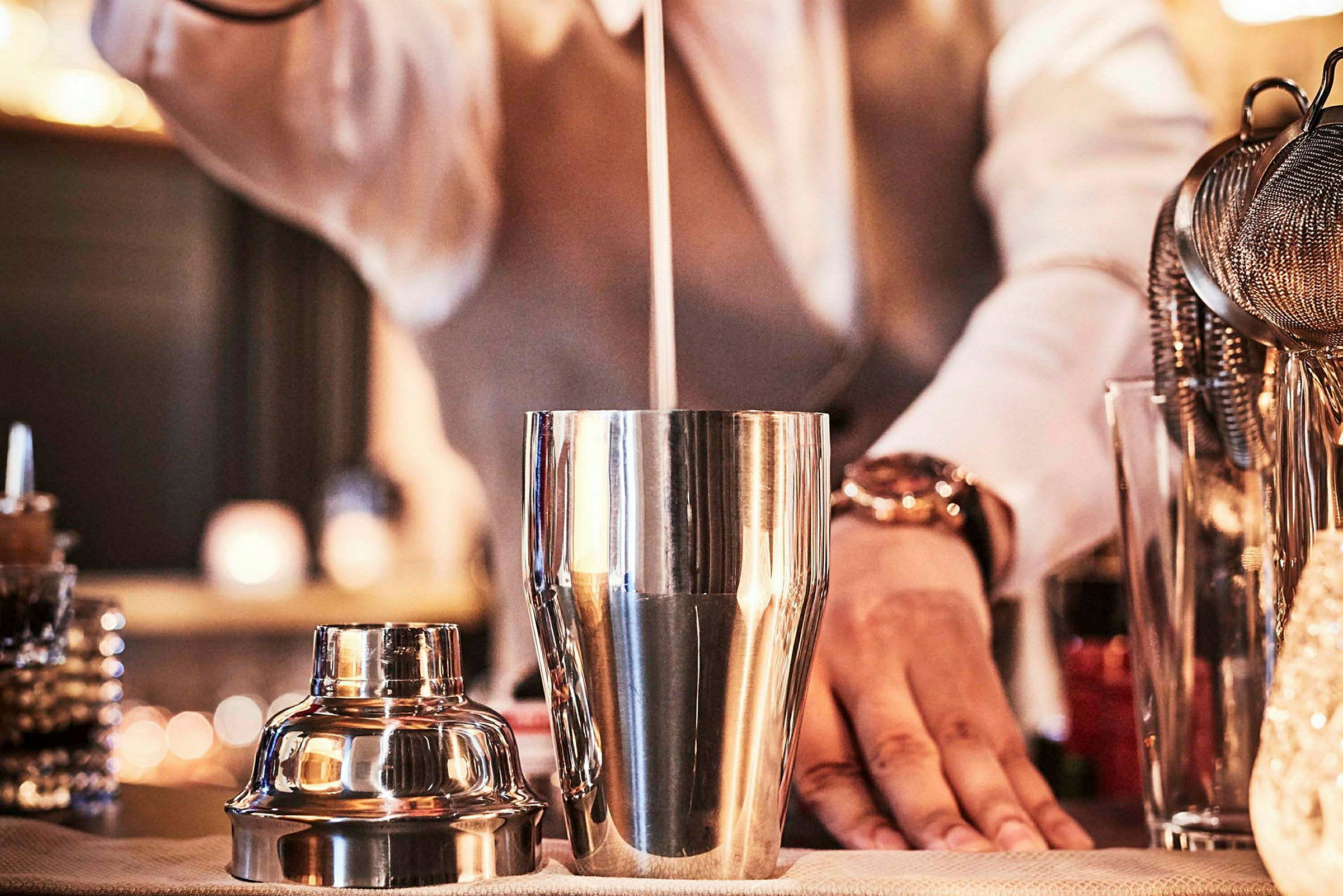 En bartender mikser en cocktail i en metalldrinks-shaker. (AI-genereret tekst)