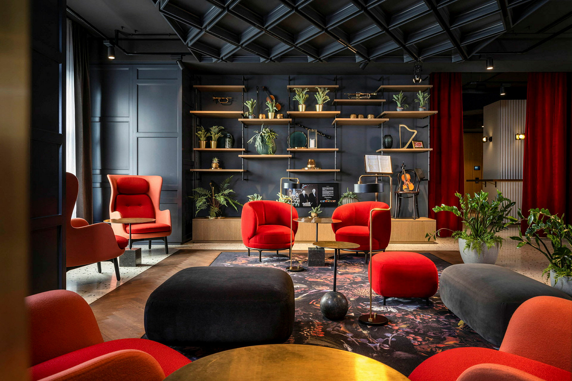 Elegant lounge med røde og sorte møbler, planter og en hylde med dekorative genstande. (AI-genereret tekst)
