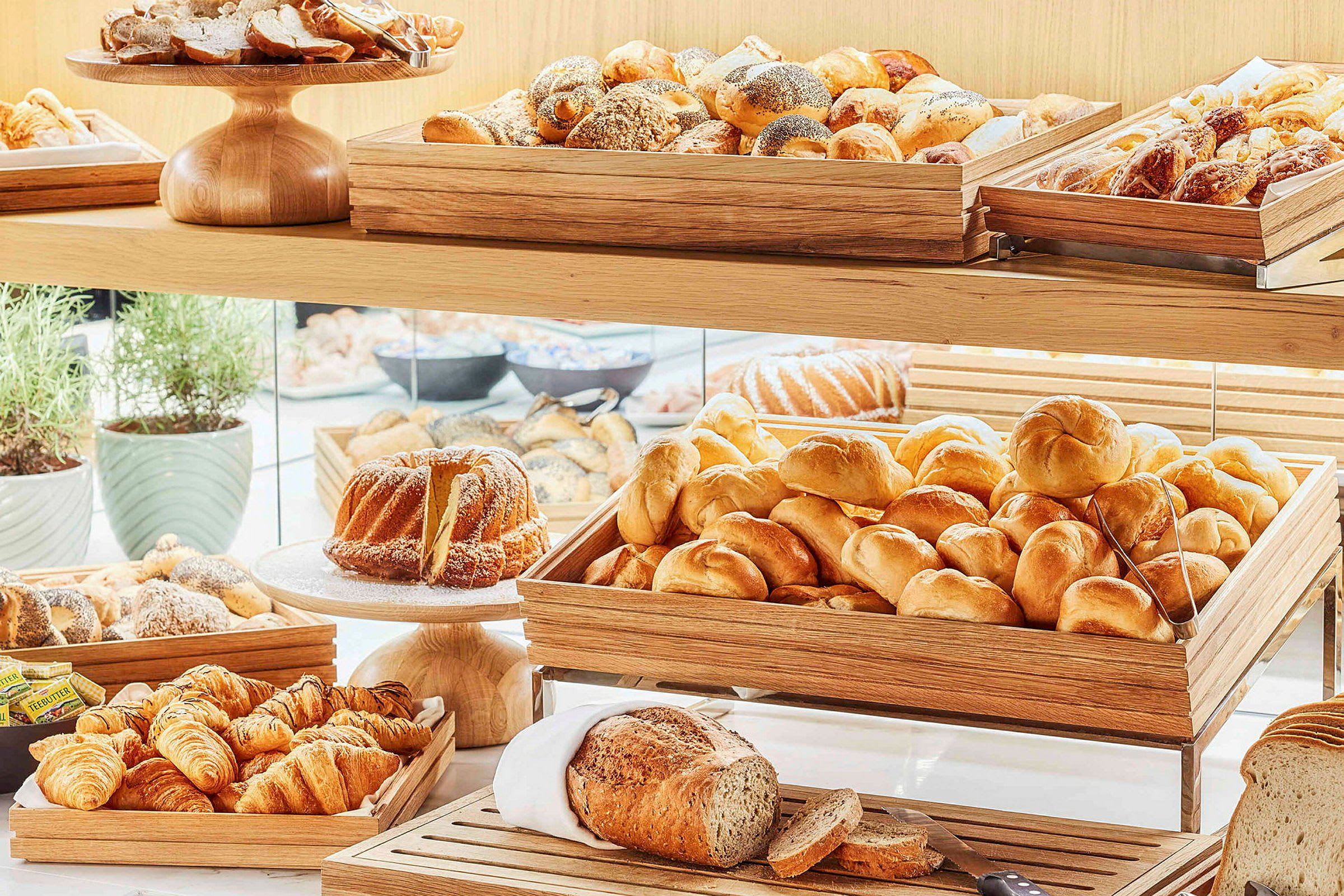 Billede af en buffet med friskbagt brød og bagværk opstillet i trækasser. (AI-genereret tekst)