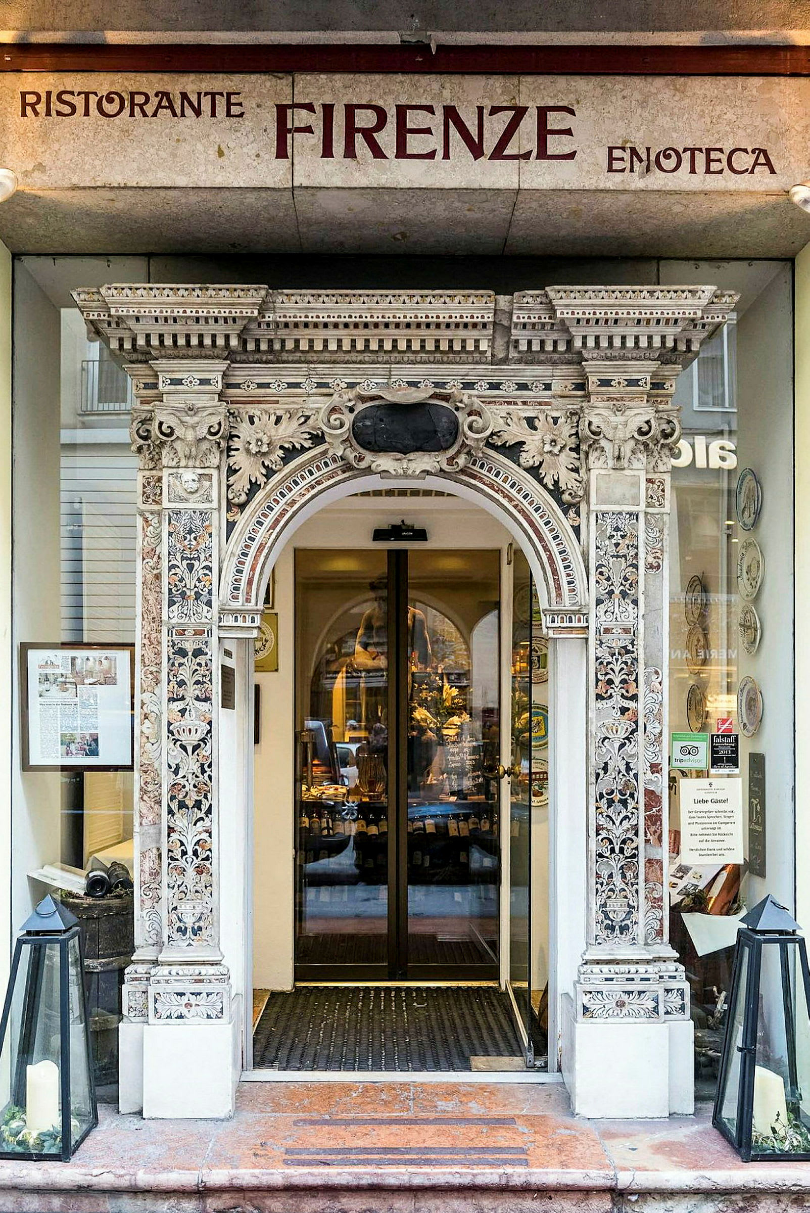 Indgang til en restaurant med dekorativ udsmykket portal og glasdøre. (AI-genereret tekst)