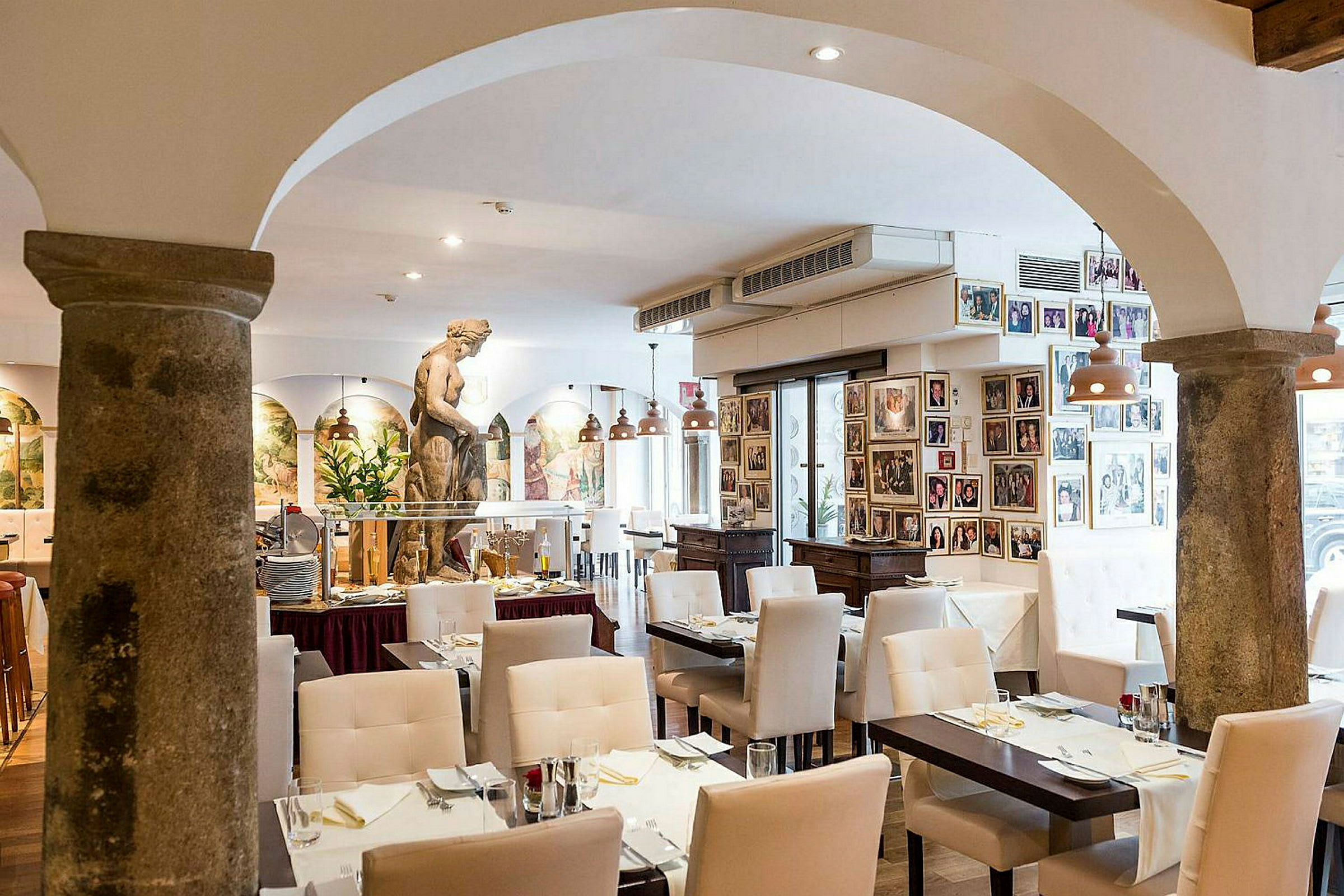 Indretning af en restaurant med hvide stole, dækkede borde og en skulptur i midten af rummet. (AI-genereret tekst)