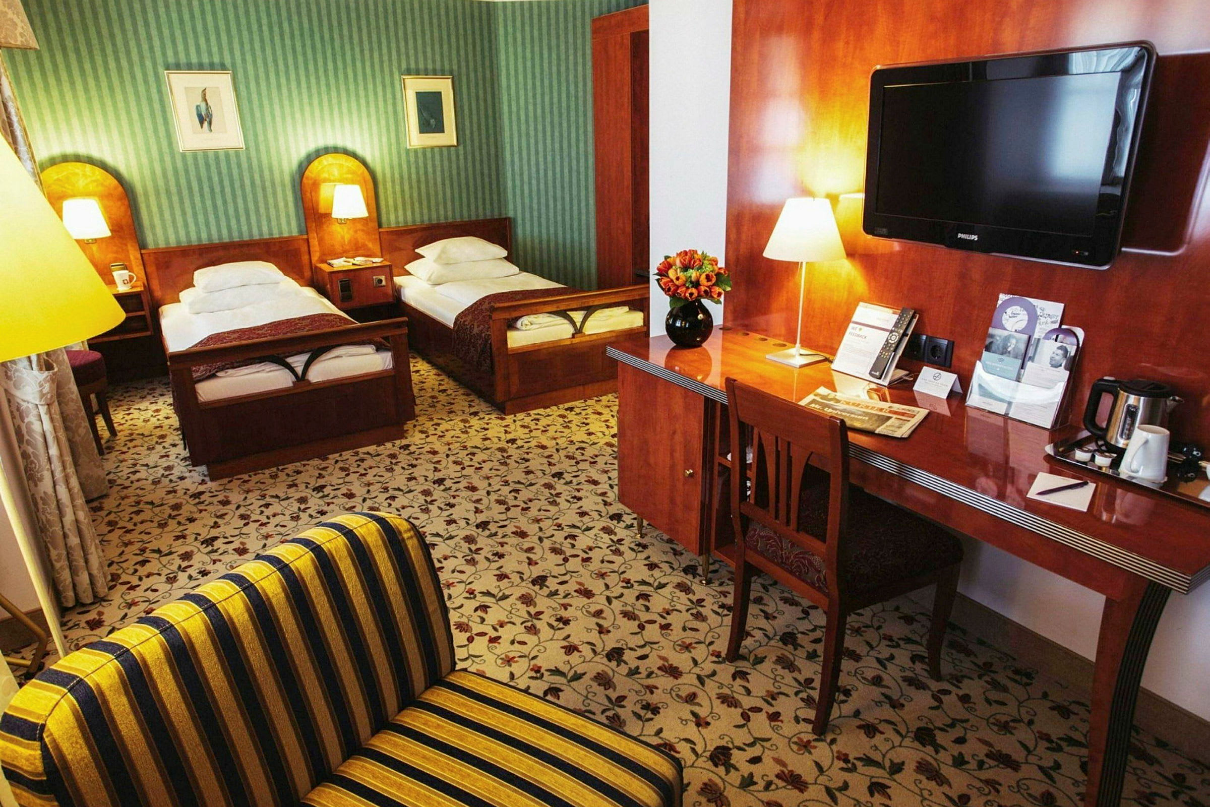 Et hotelværelse med to enkeltsenge, et skrivebord med blomster og et tv. (AI-genereret tekst)