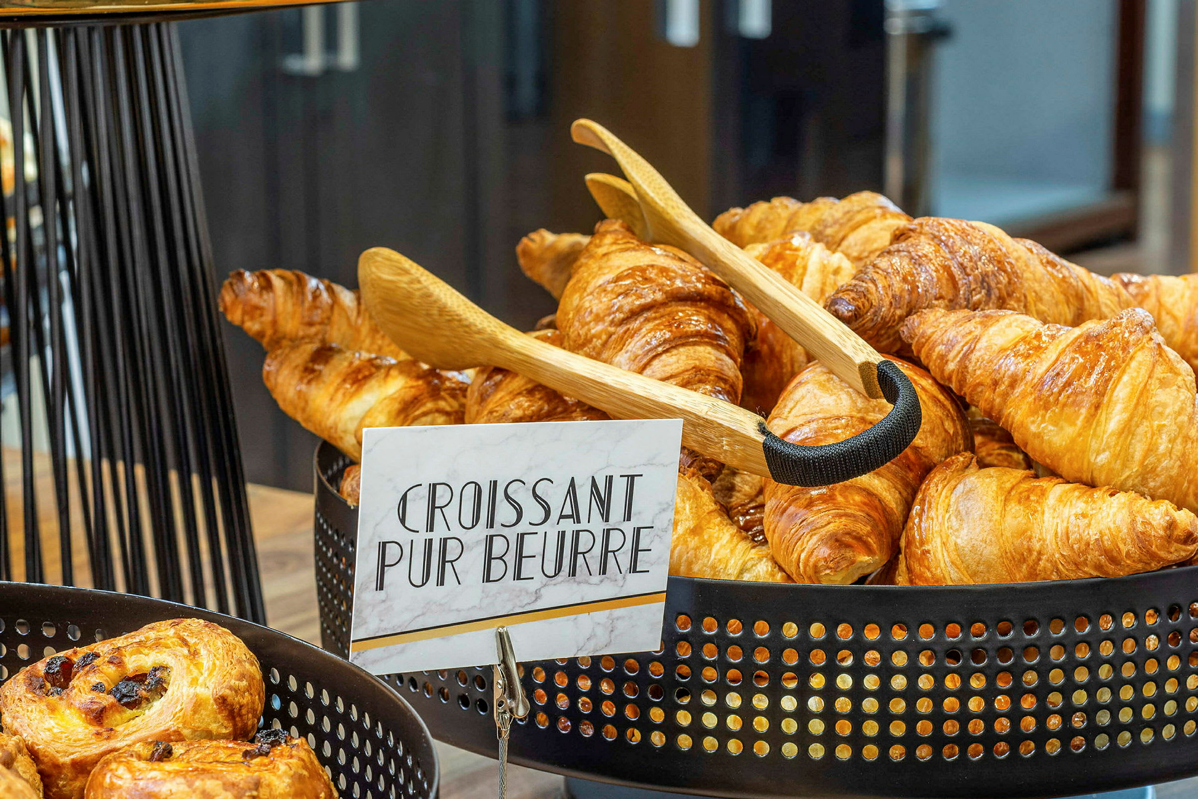 En kurv fyldt med nybagte croissanter med et skilt, der siger 'Croissant Pur Beurre'. (AI-genereret tekst)