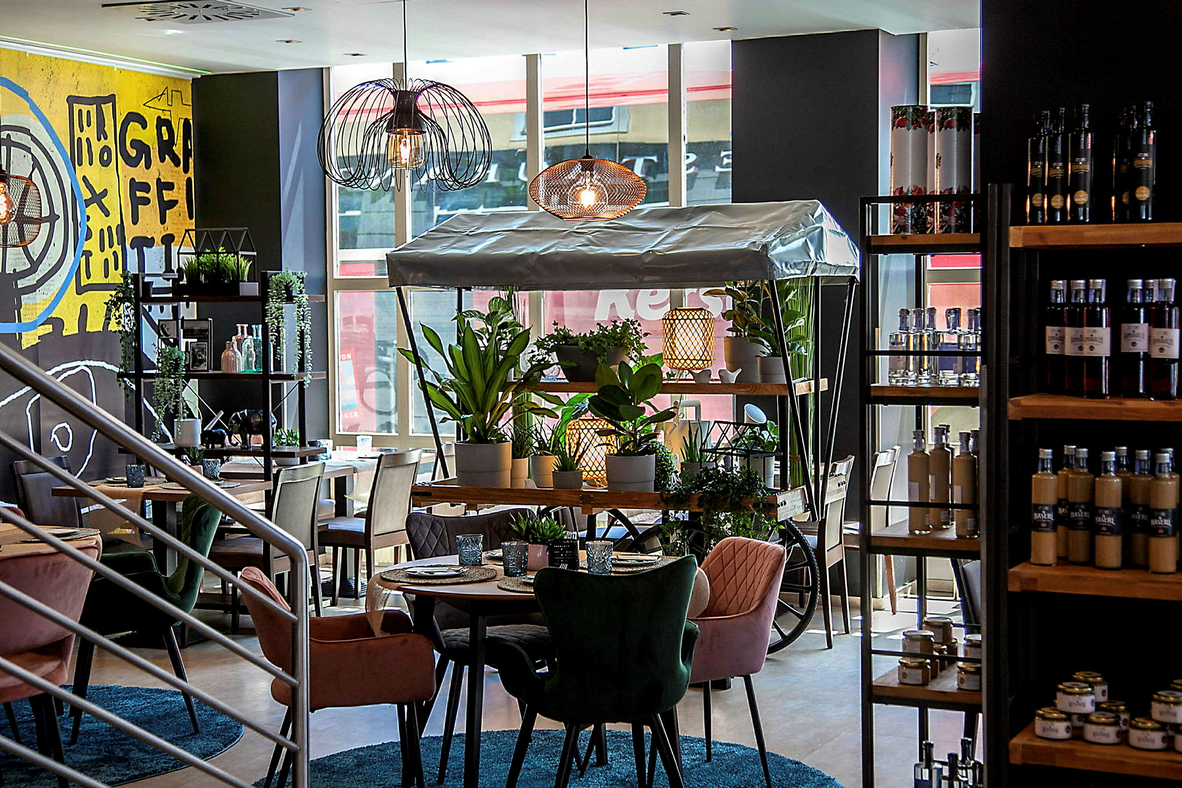 Interiør af en moderne café med farverige stole, grønne planter og en dekorativ plantevogn. (AI-genereret tekst)