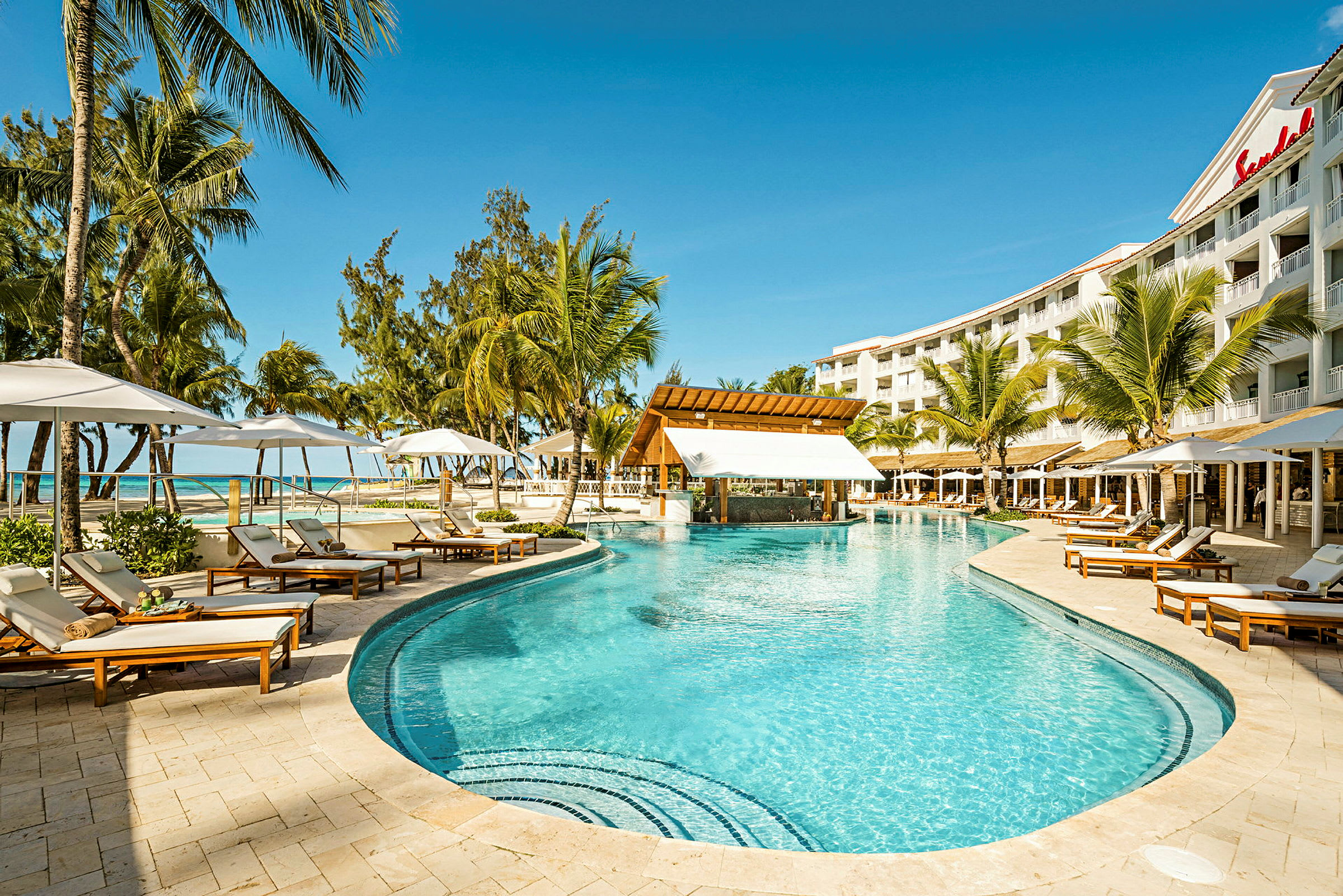 Poolområde ved Sandals hotel med liggestole og palmer. (AI-genereret tekst)