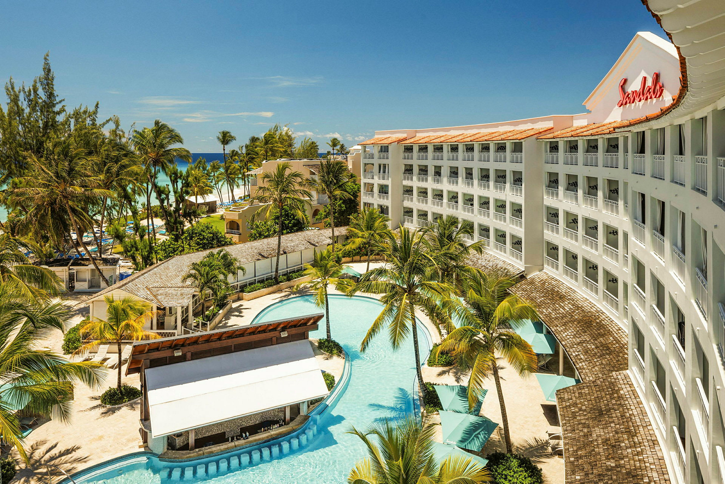 Et hotel med pool, omgivet af palmer og nærliggende strand. (AI-genereret tekst)