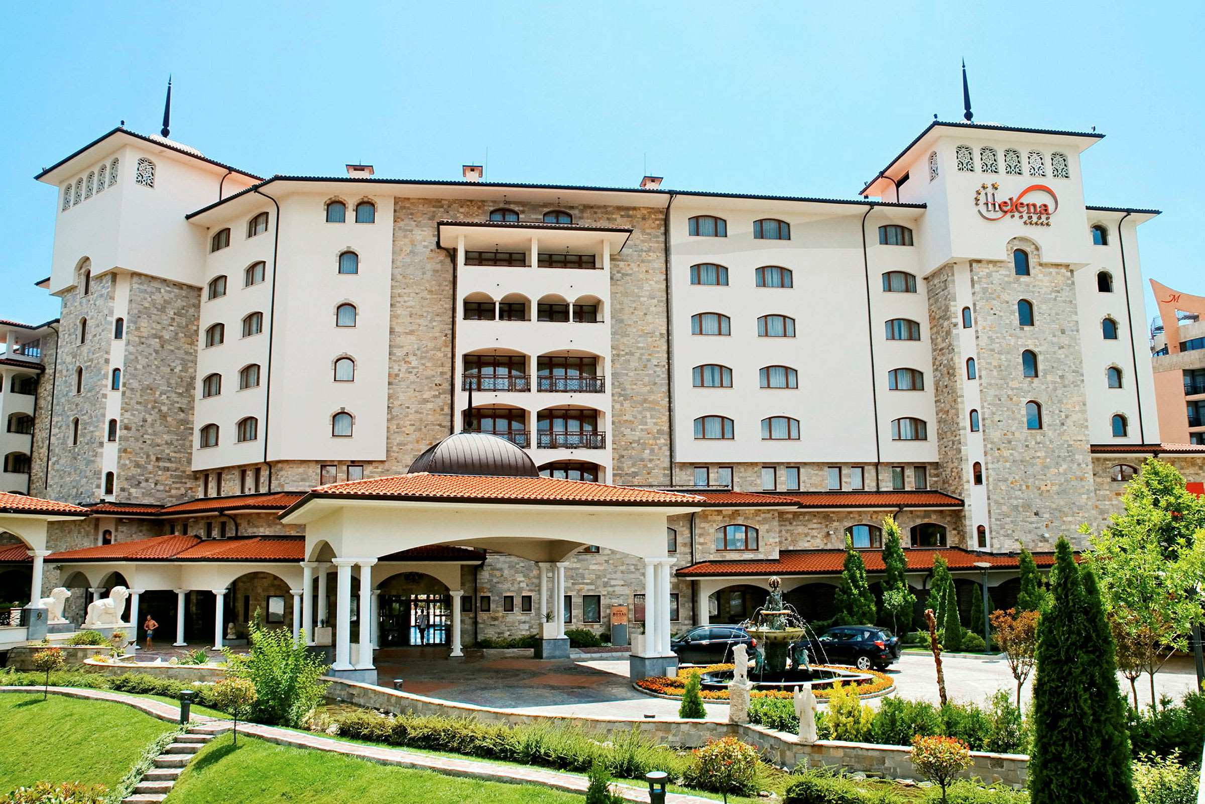 Et hotel med en moderne og elegant facade, omgivet af en smukt anlagt have. (AI-genereret tekst)