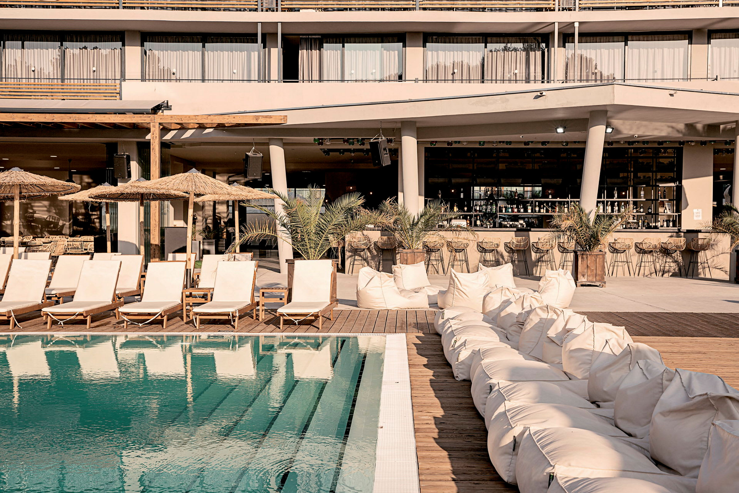 En pool med liggestole og sækkestole ved et hotelområde. (AI-genereret tekst)