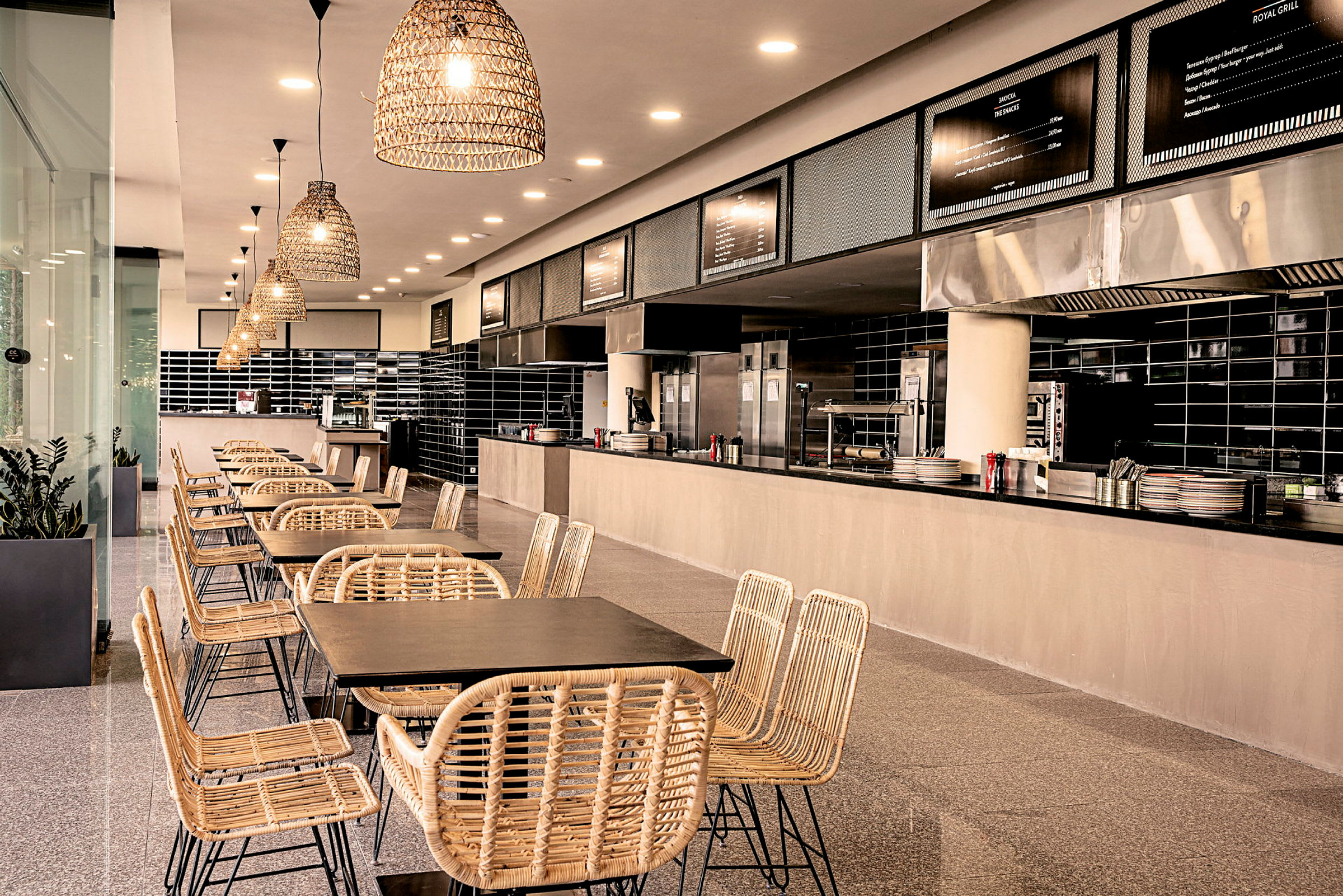 Moderne restaurantmiljø med naturfarvede stole og borde foran et åbent køkken. (AI-genereret tekst)