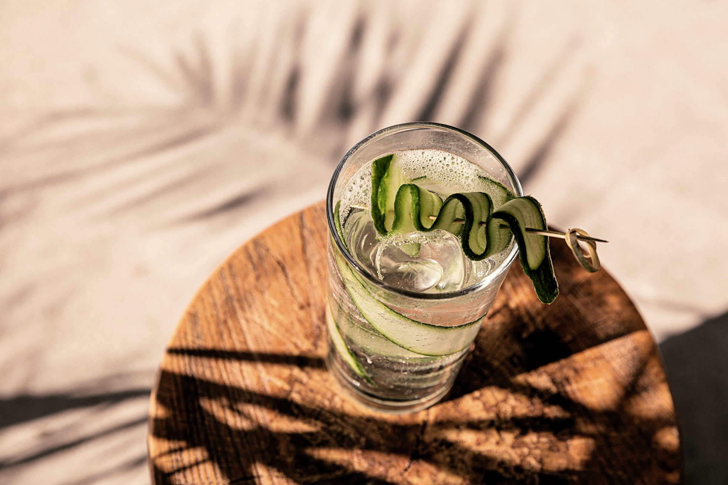 Et glas med is og dekorativ agurk på et træbord. (AI-genereret tekst)