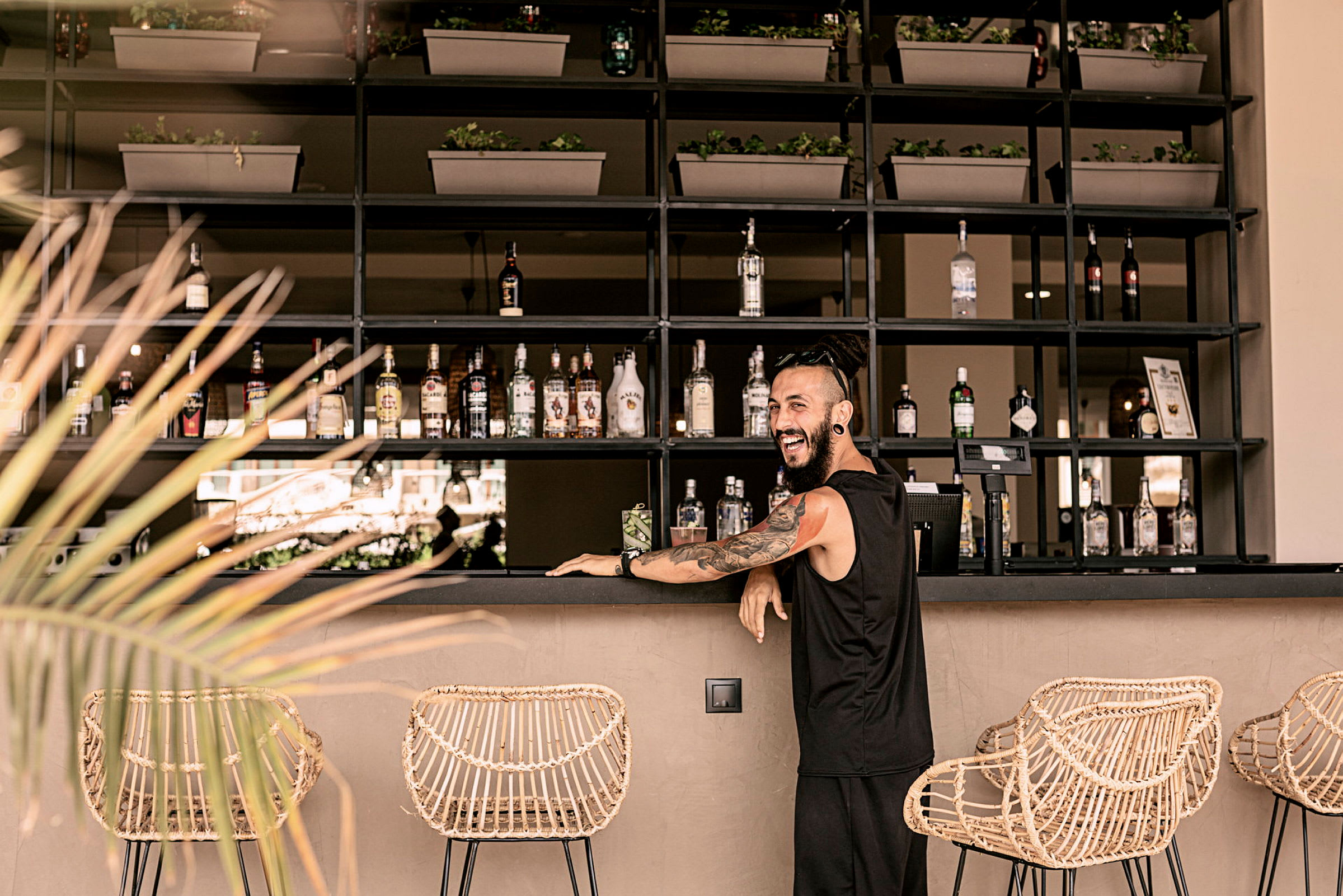 En elegant bar med flasker, kurvestole og plantepynt. (AI-genereret tekst)