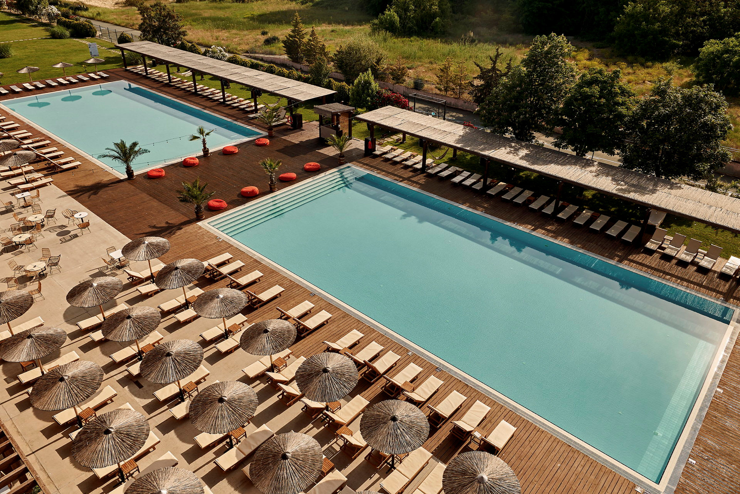 To store swimmingpools omgivet af solsenge og parasoller. (AI-genereret tekst)