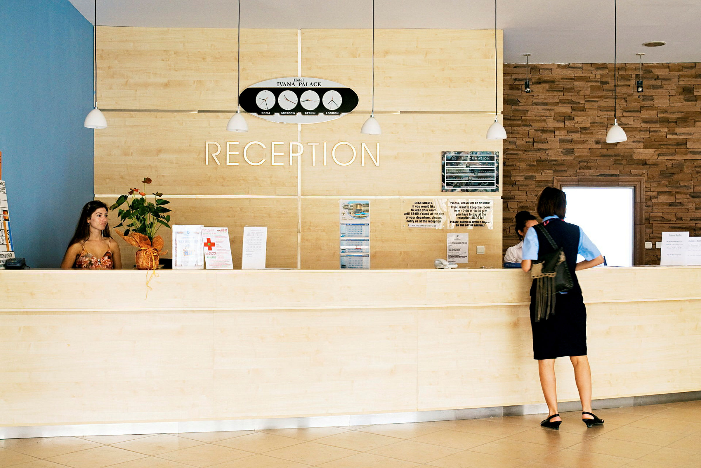 Reception med lyst træinteriør og en person, der står ved skranken. (AI-genereret tekst)