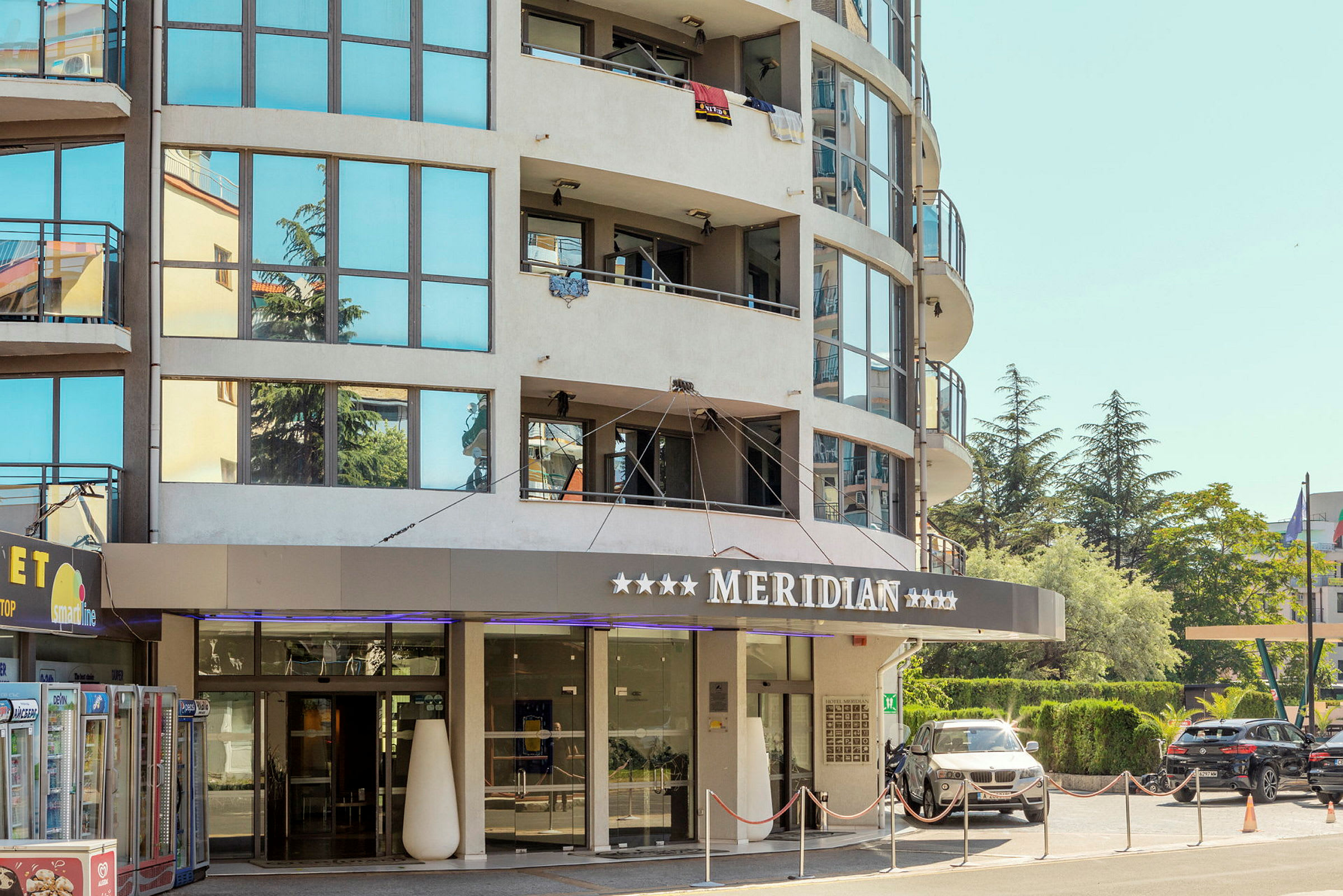 Et hotel med glasfacade og teksten 'Meridian' over indgangen. (AI-genereret tekst)