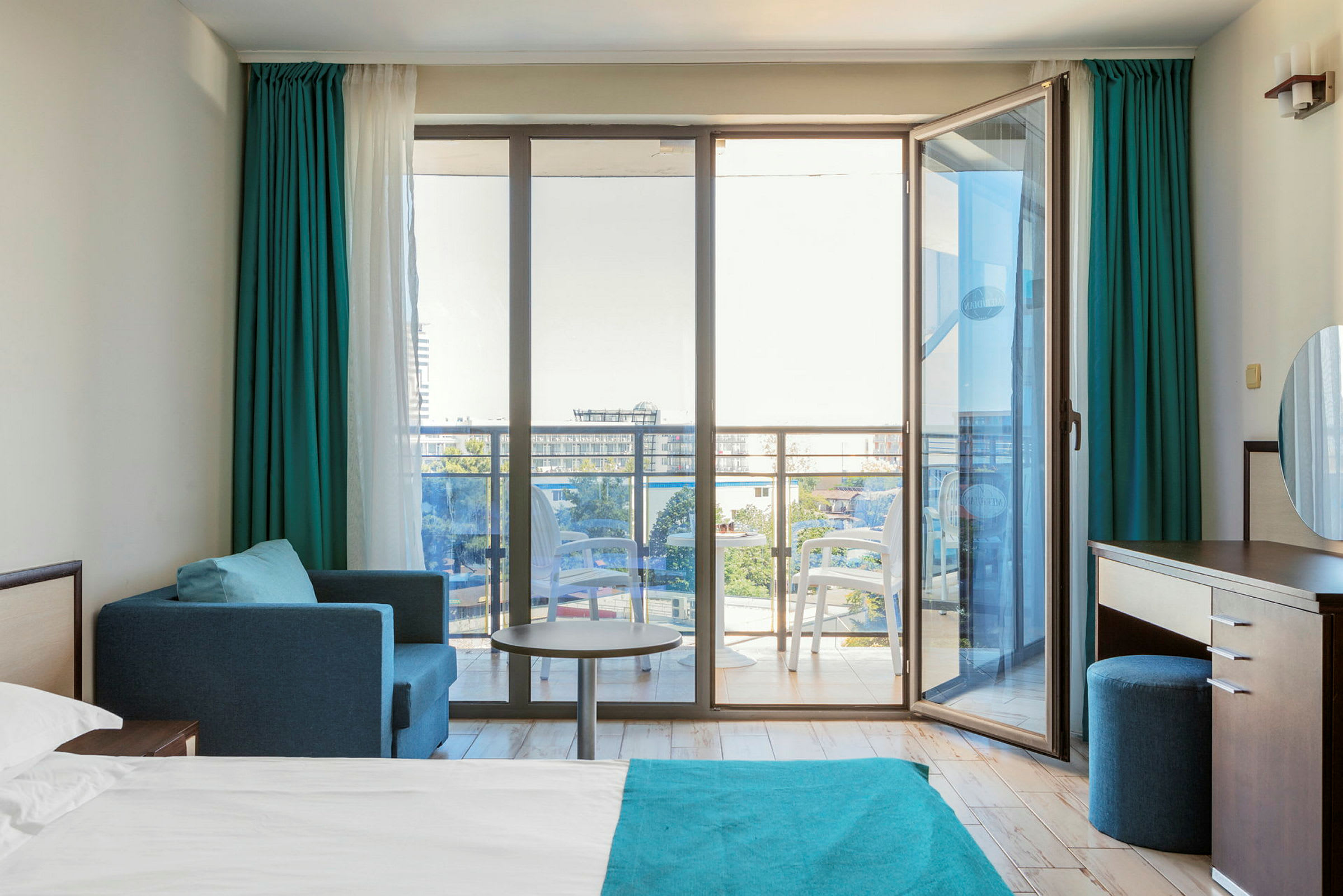 Moderne hotelværelse med en seng, siddeområde og glasdøre ud til en balkon. (AI-genereret tekst)