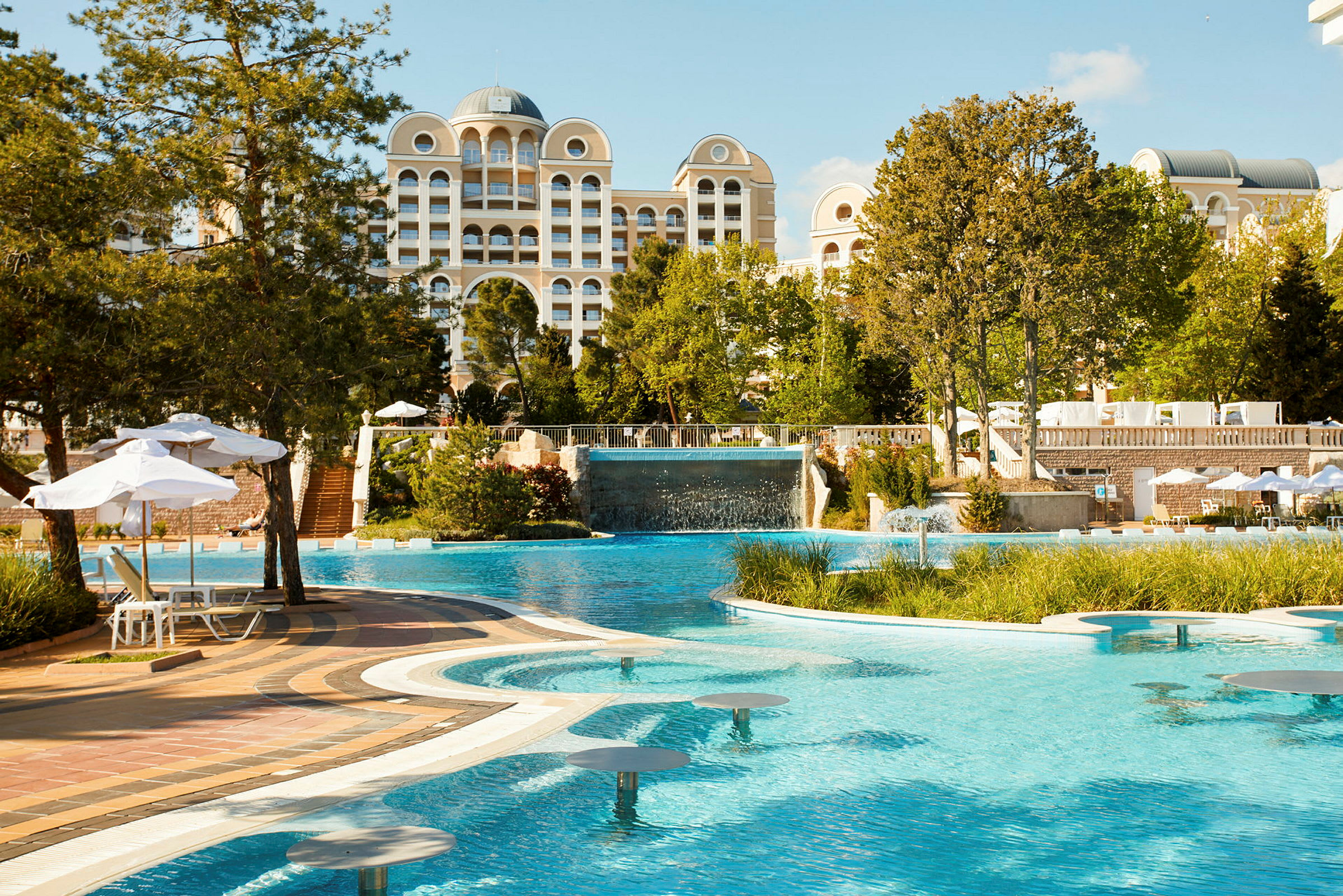 Hotel med poolområde og omkringliggende haver. (AI-genereret tekst)
