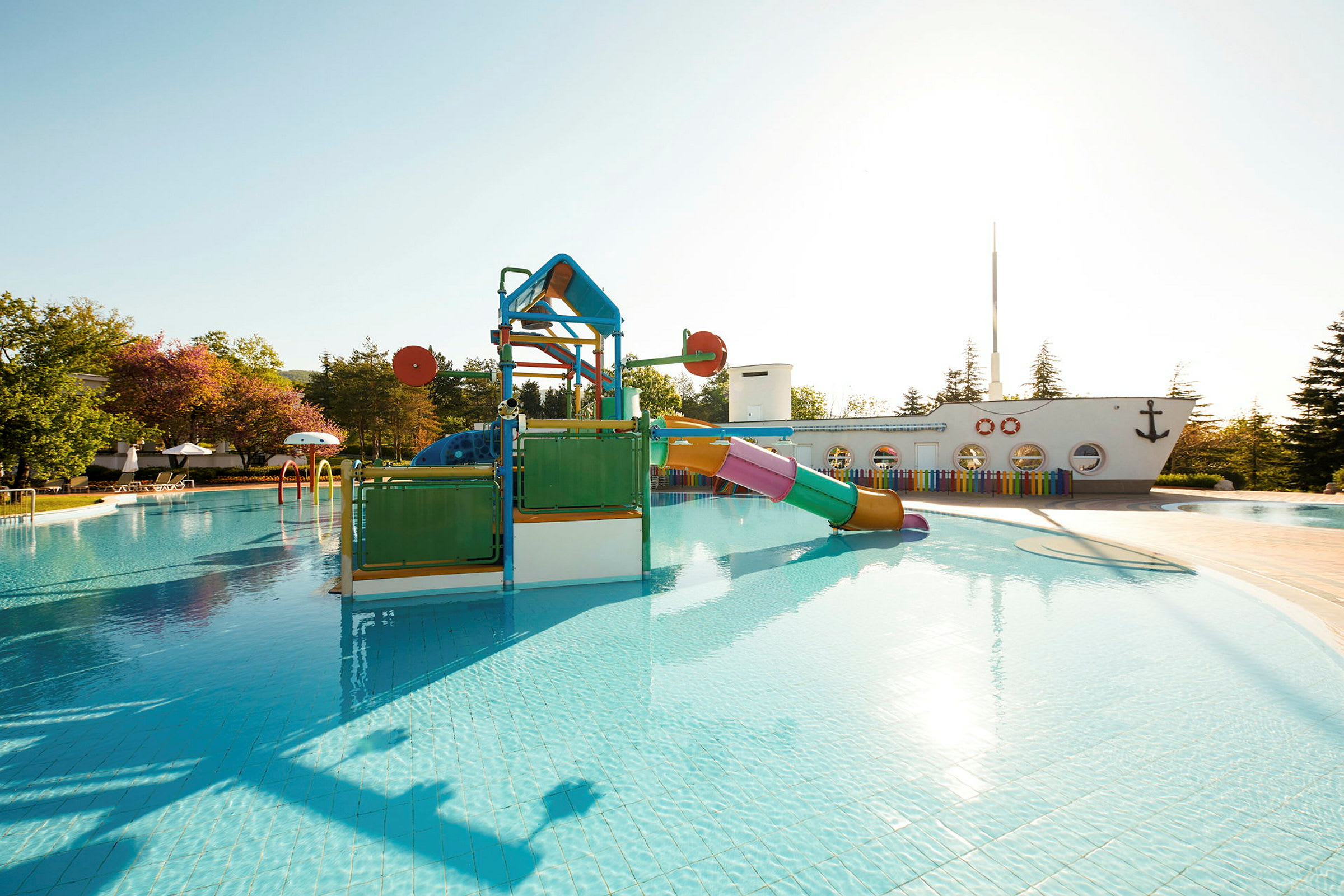 Udendørs swimmingpool med legeplads og rutsjebane. (AI-genereret tekst)