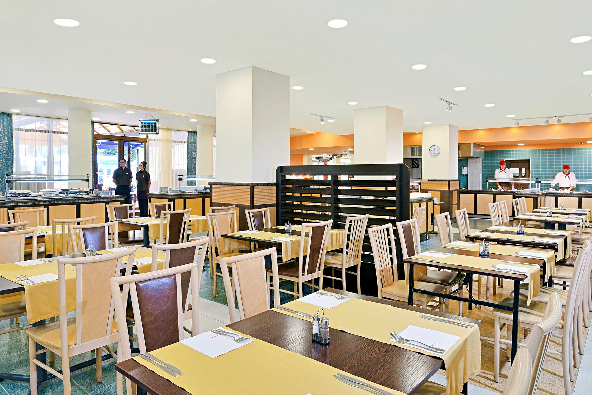 Restaurant med opstillede borde og stole, klar til gæster, i en lys og rummelig spisesal. (AI-genereret tekst)