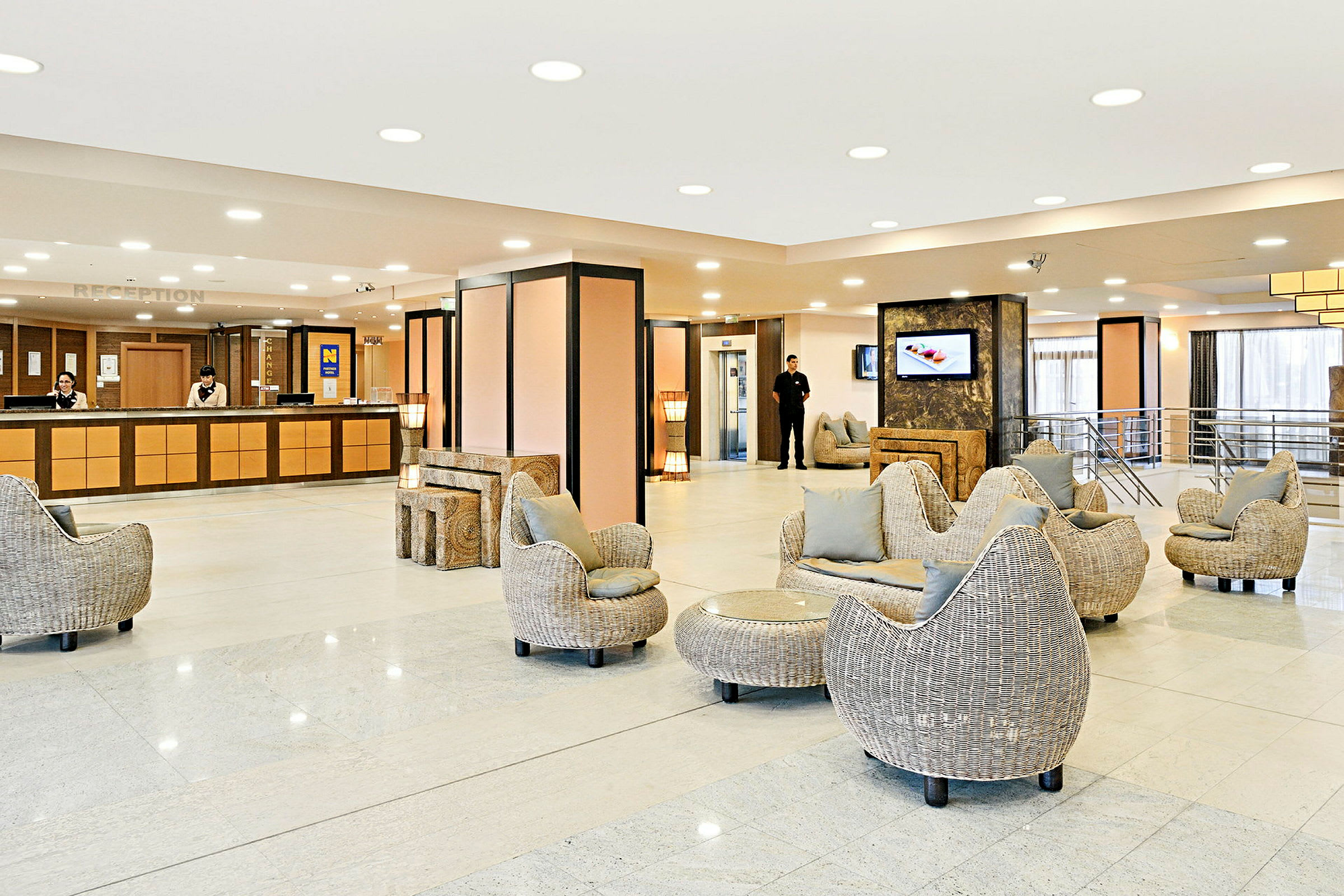 Hotellobby med receptionsdisk, siddegrupper og lyse moderne møbler. (AI-genereret tekst)