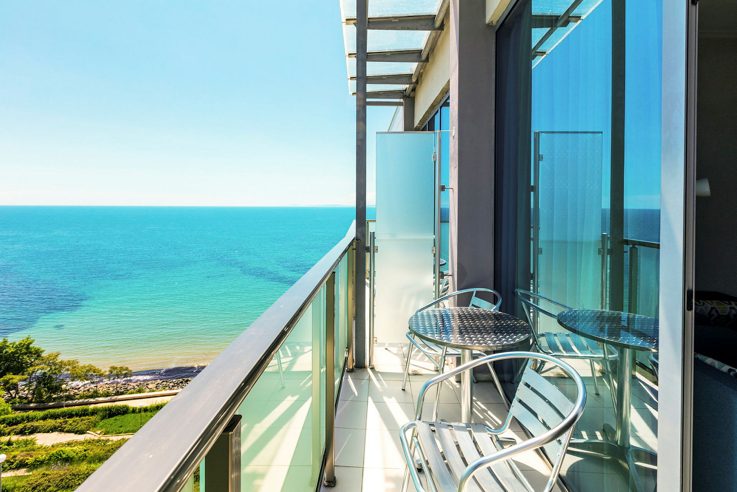 En altan med havemøbler og udsigt over havet og en klar blå himmel. (AI-genereret tekst)