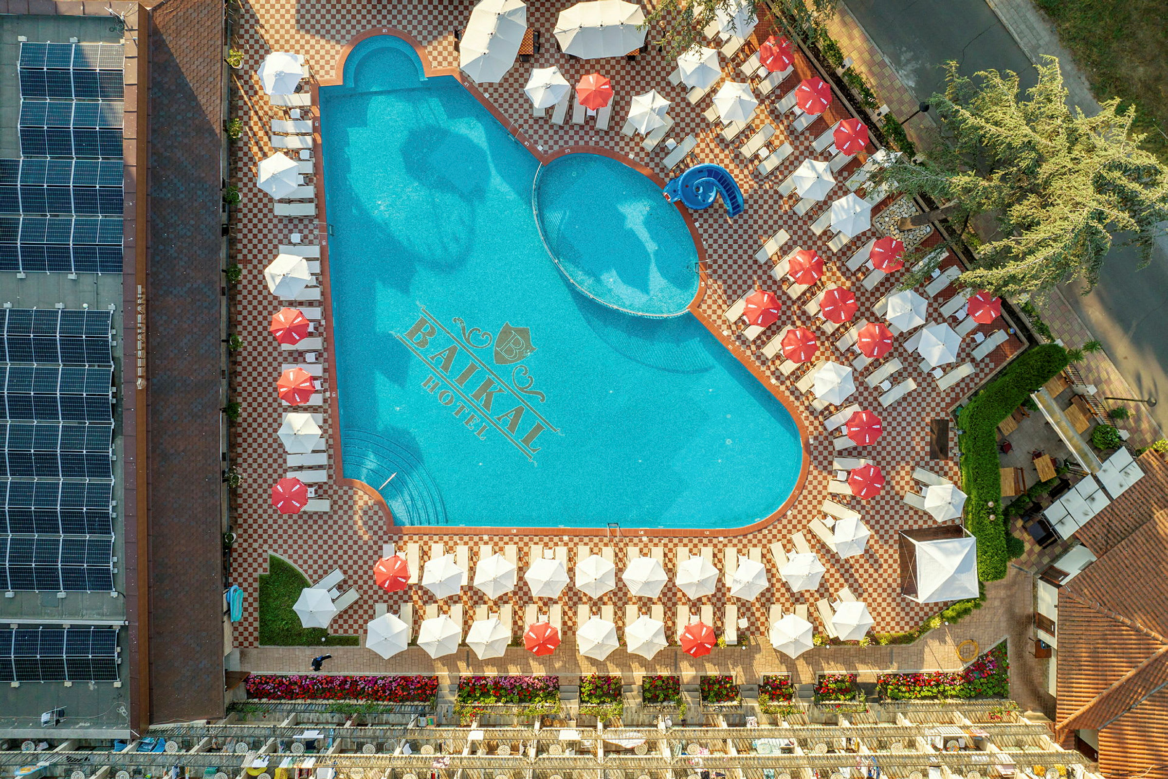 Et luftfoto af en udendørs pool omgivet af liggestole og parasoller ved Baikal Hotel. (AI-genereret tekst)