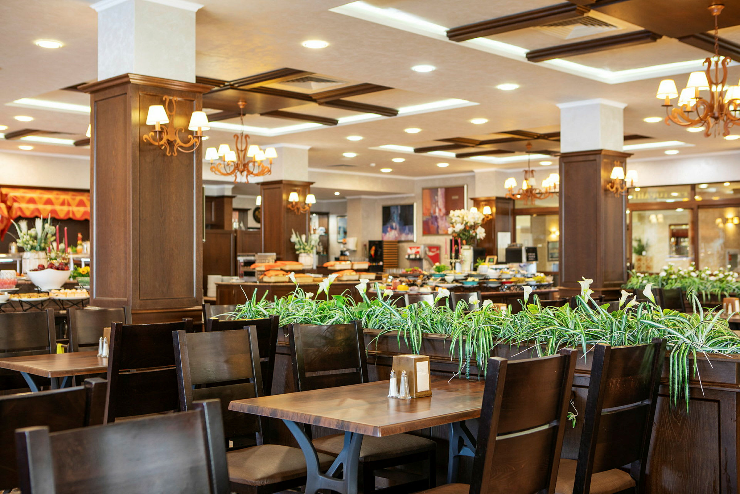 Interiør af en restaurant med mørke træborde og stole, grønne planter som dekoration. (AI-genereret tekst)