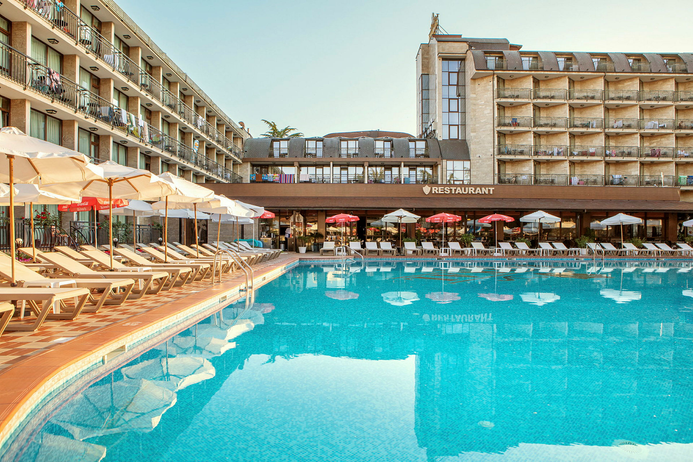 Udendørs pool ved et hotel med solsenge og parasoller. (AI-genereret tekst)