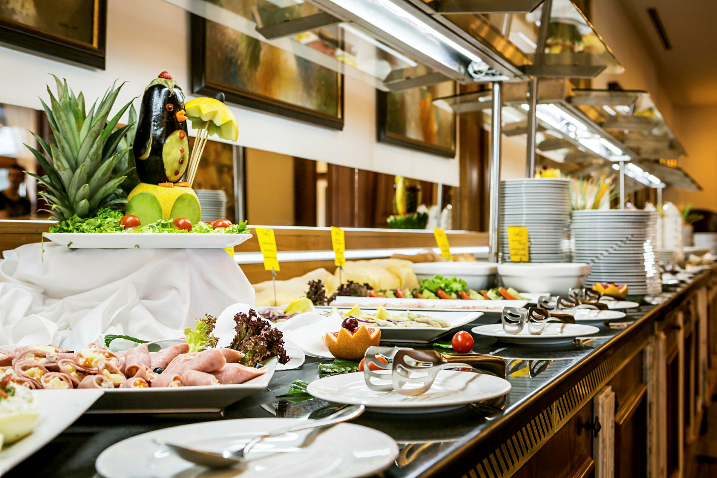 Buffetbord med forskellige retter herunder salat, pålæg og pyntet frugt. (AI-genereret tekst)