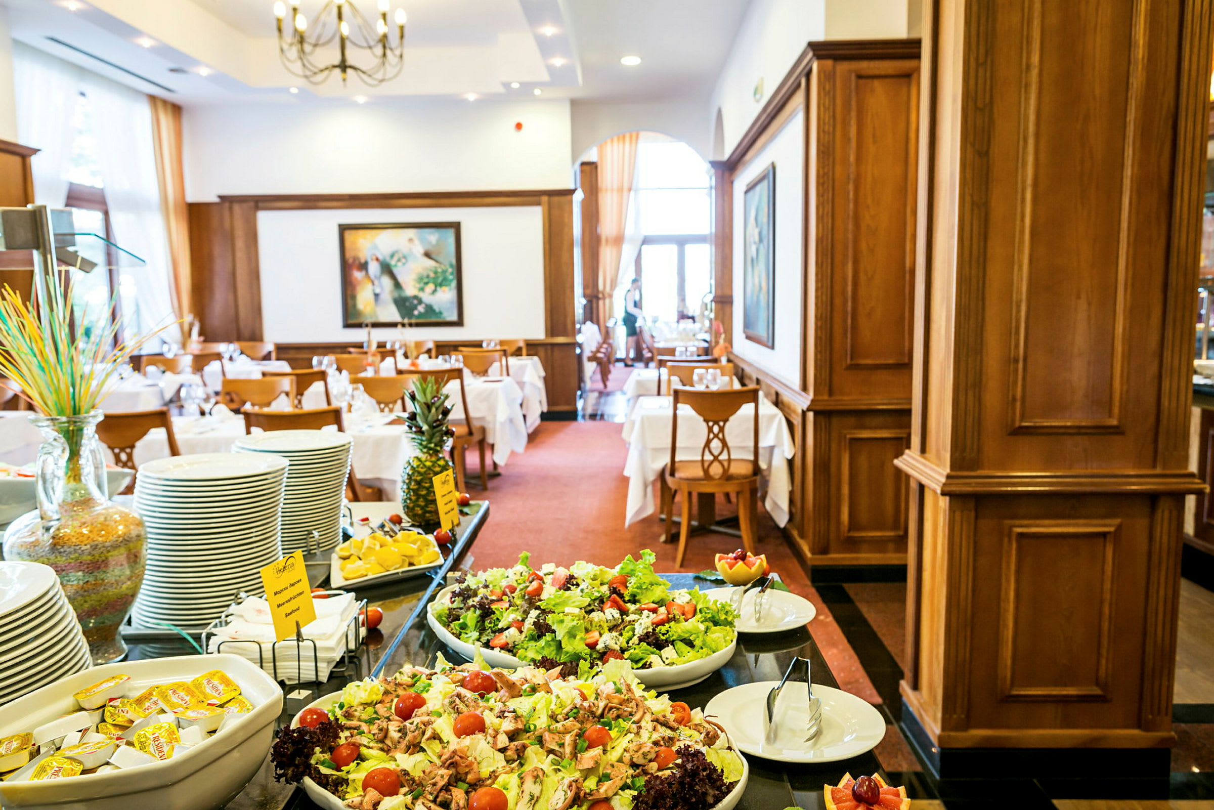 Buffetbord med salat, frugt og porcelæn i en elegant indrettet restaurant. (AI-genereret tekst)