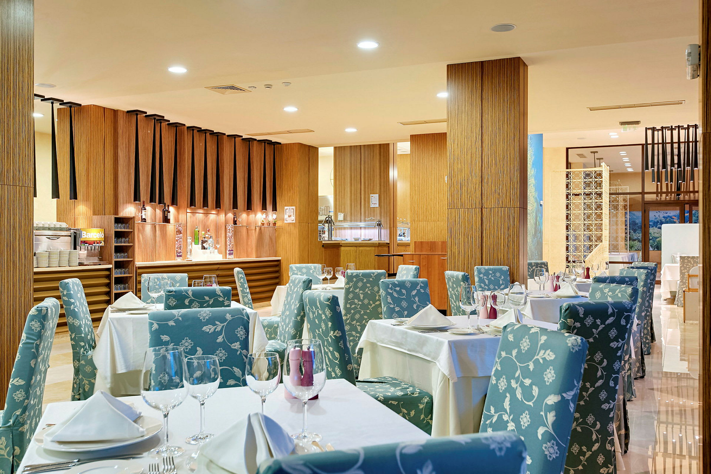 Interiør af en moderne restaurant med dækkede borde og komfortable stole. (AI-genereret tekst)