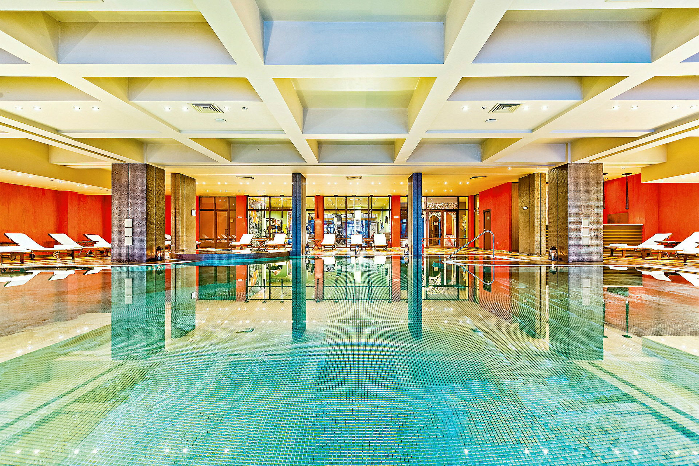 En indendørs swimmingpool med liggestole langs væggene og en moderne indretning. (AI-genereret tekst)
