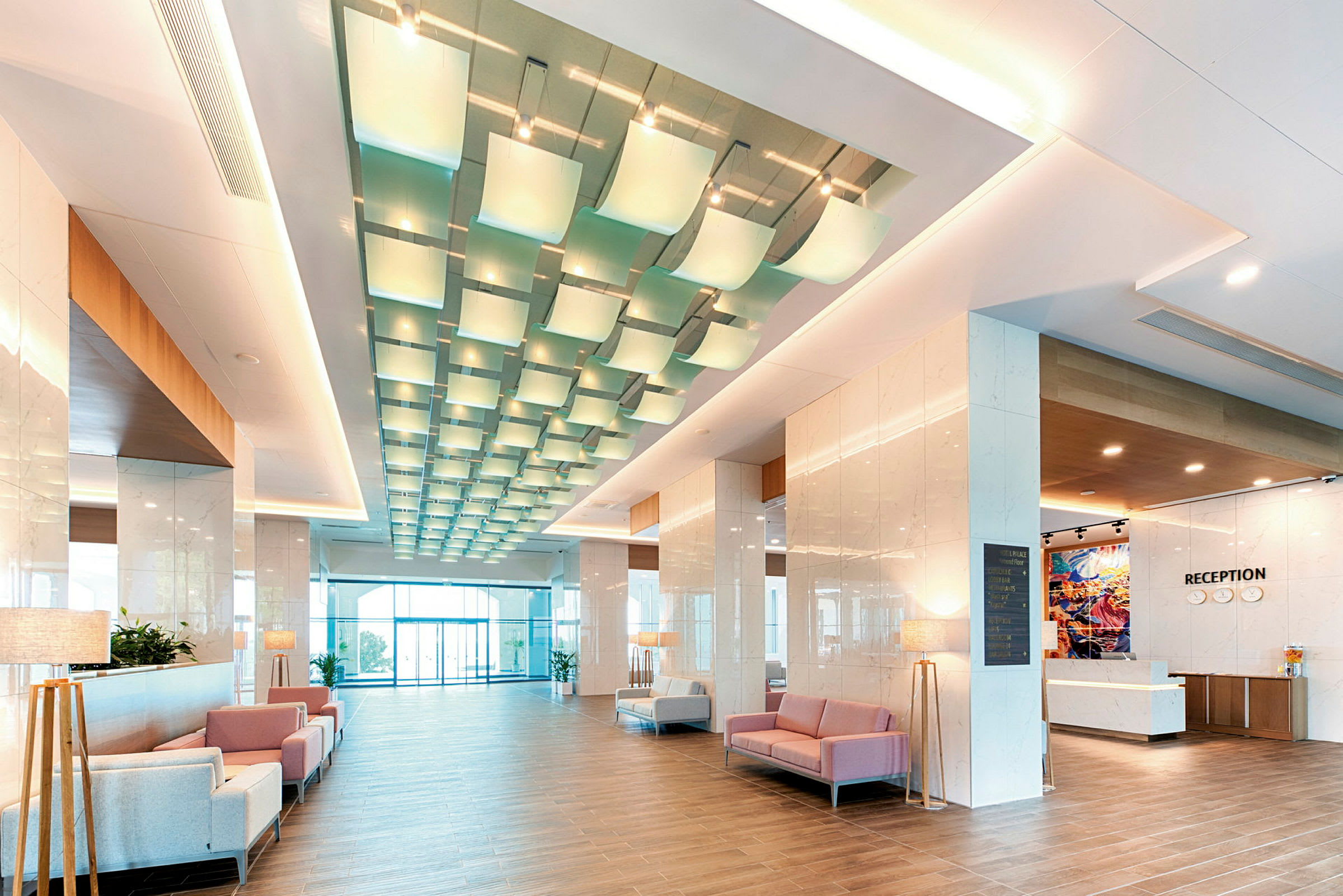 Et billede af en moderne hotellobby med siddepladser, reception og dekorativ belysning. (AI-genereret tekst)