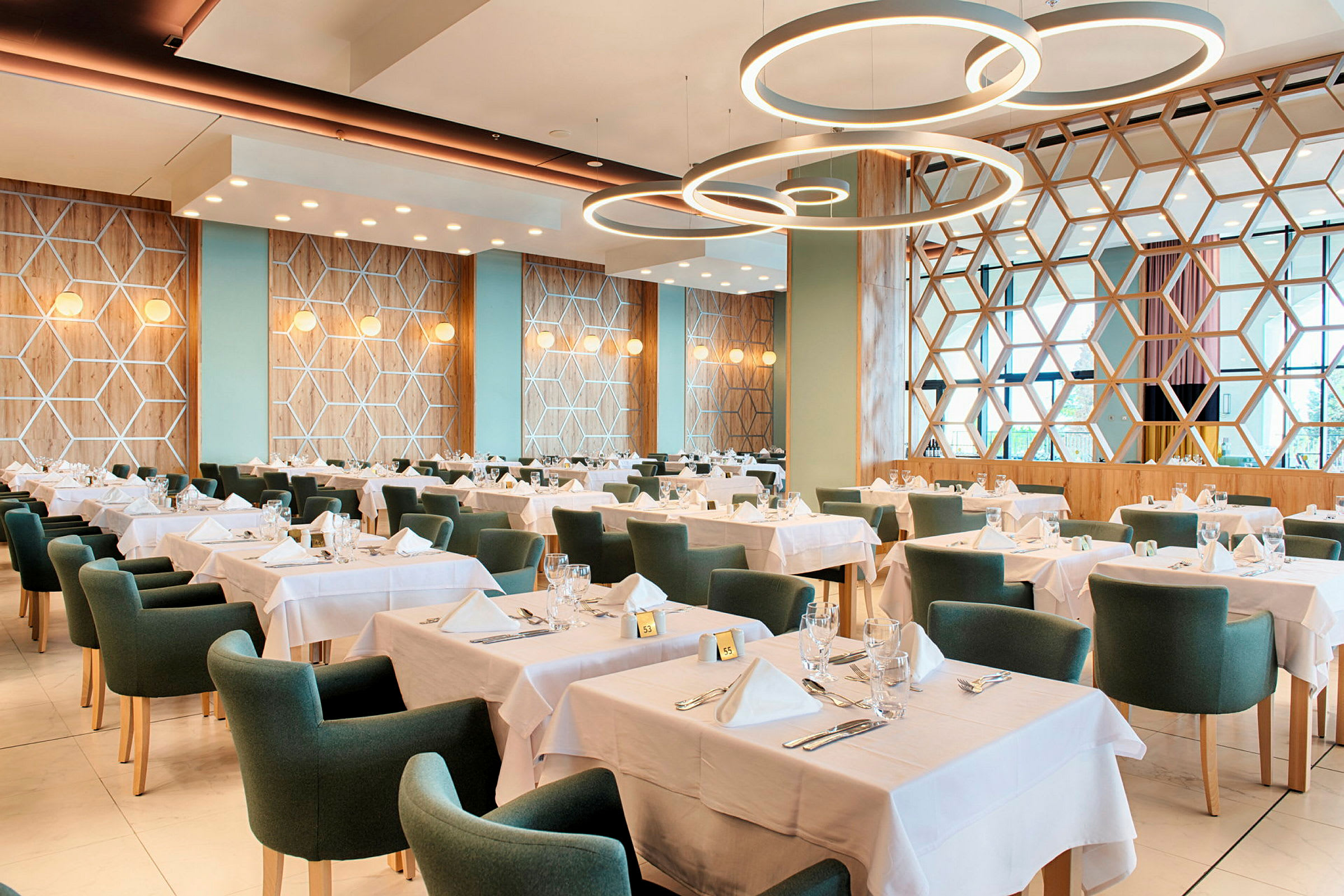 Billede af en restaurant med dækkede borde og grønne stole. (AI-genereret tekst)