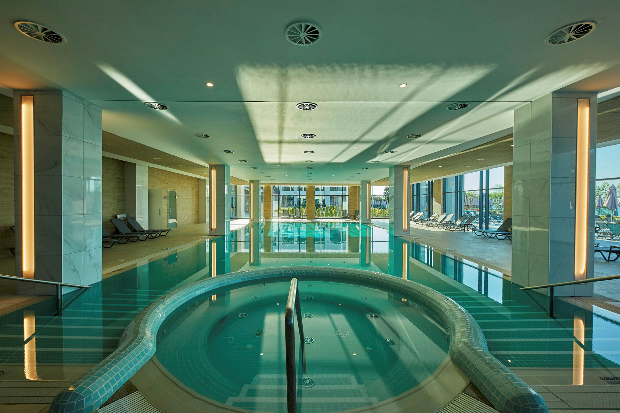 Indendørs poolområde med siddepladser og jacuzzi. (AI-genereret tekst)