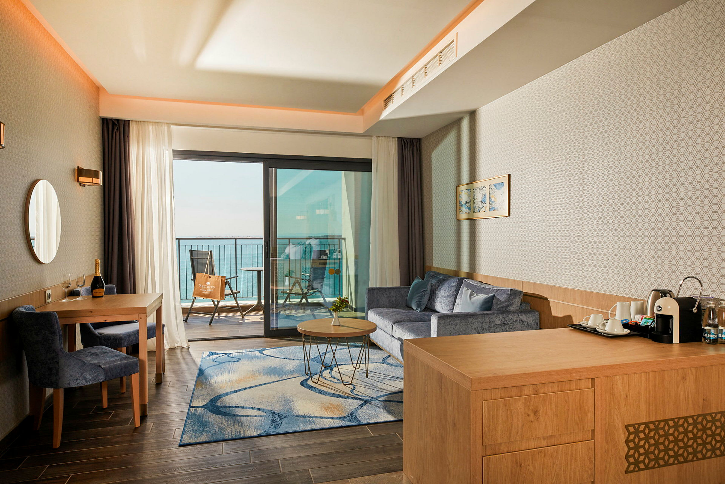Hotelværelse med siddeområde og udsigt over havet fra altanen. (AI-genereret tekst)