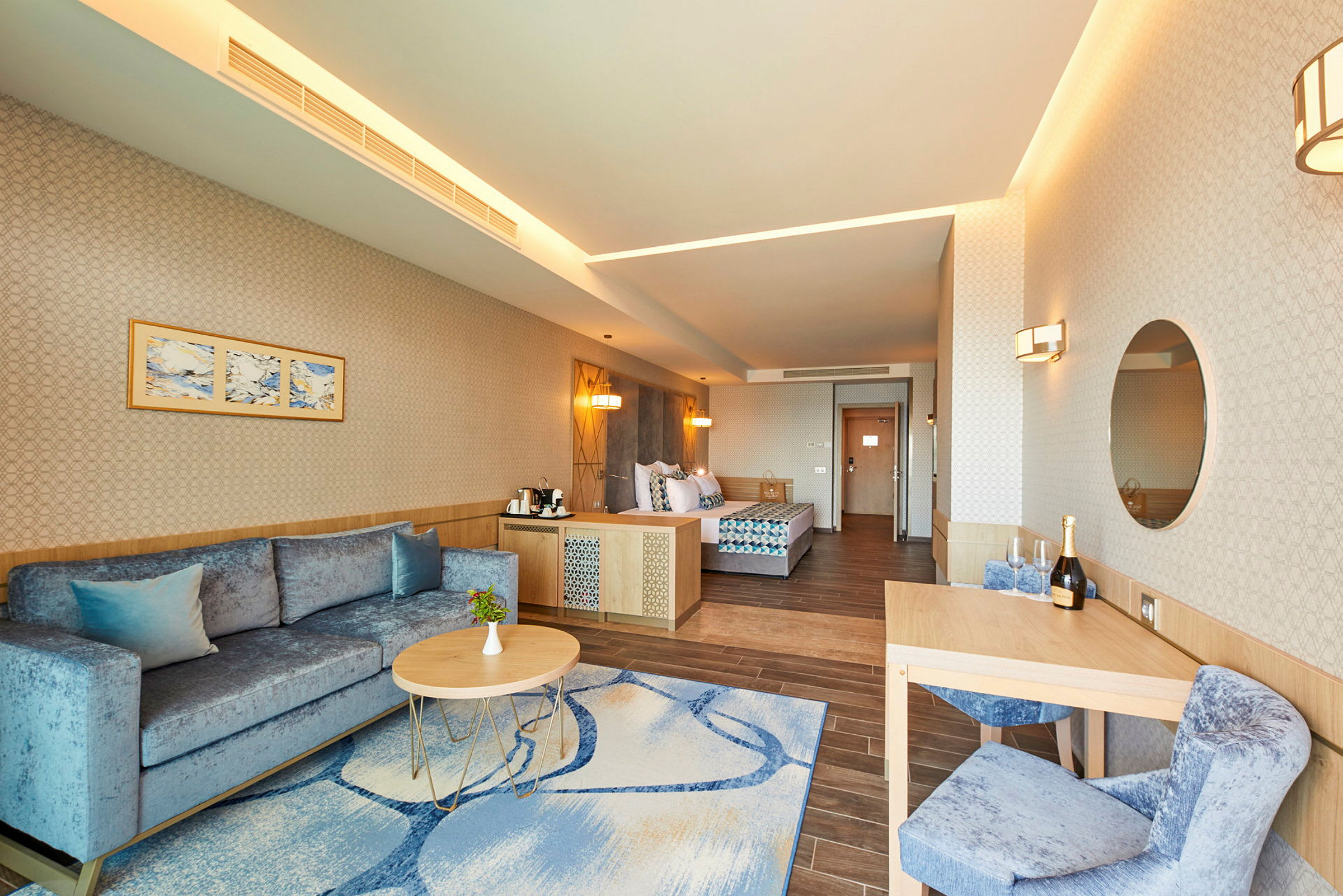 Interiør af et hotelværelse med en sofa, sofabord, spisebord og en seng. (AI-genereret tekst)