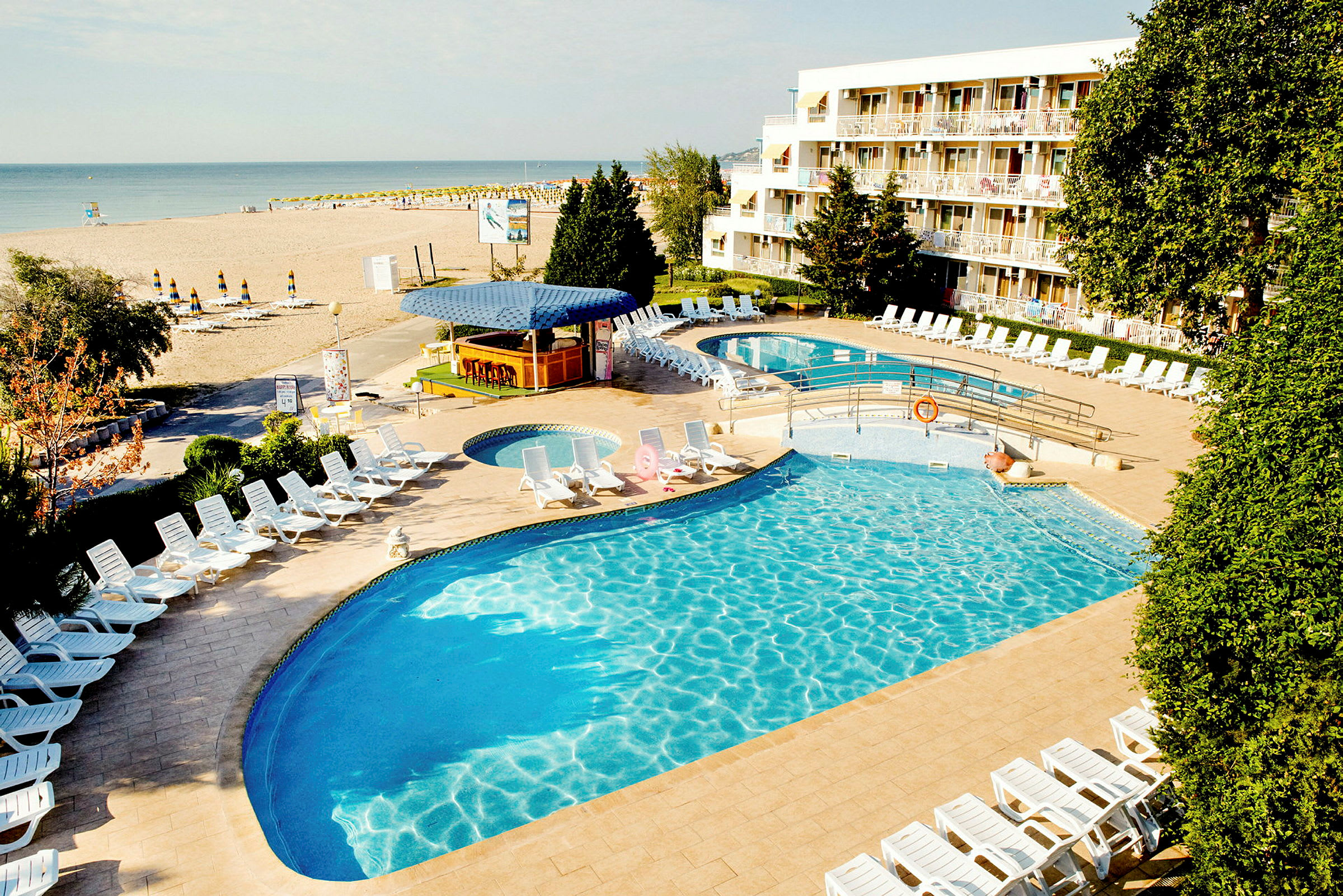 En hotelpool med liggestole og en strand i baggrunden. (AI-genereret tekst)
