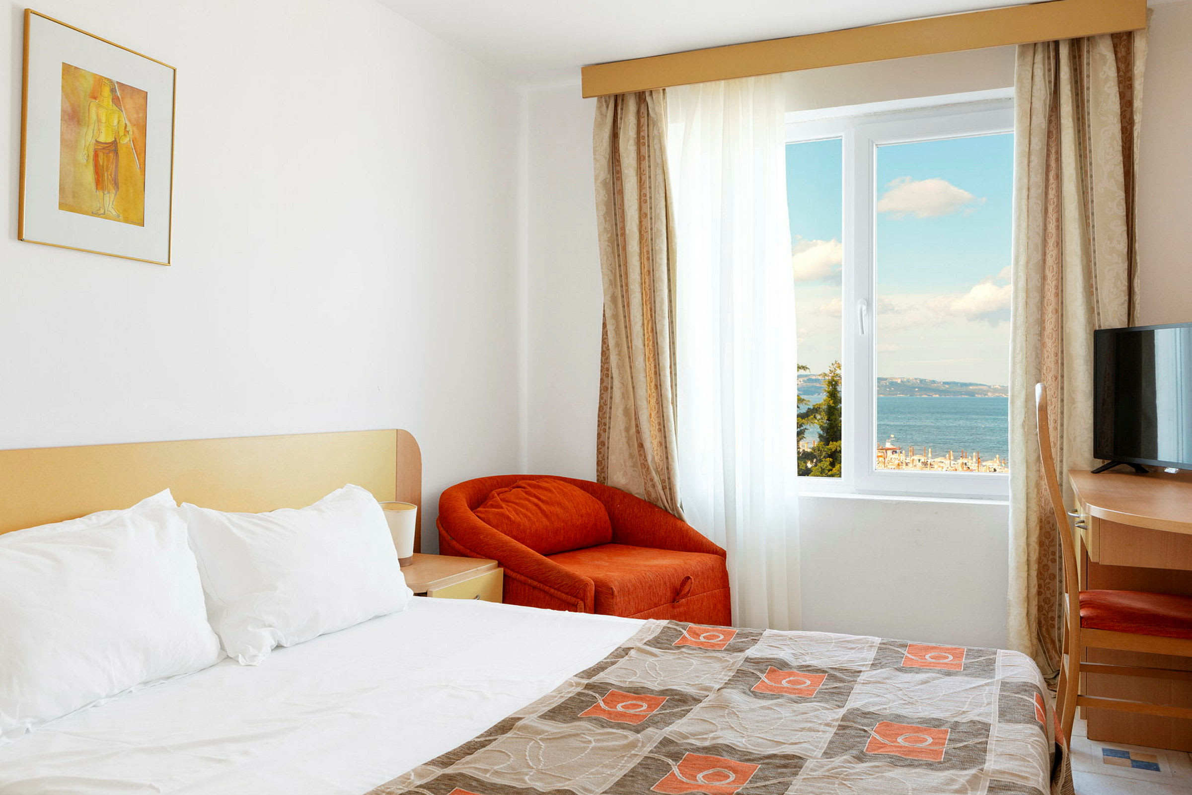 Hotelværelse med en redt seng og udsigt til havet gennem vinduet. (AI-genereret tekst)