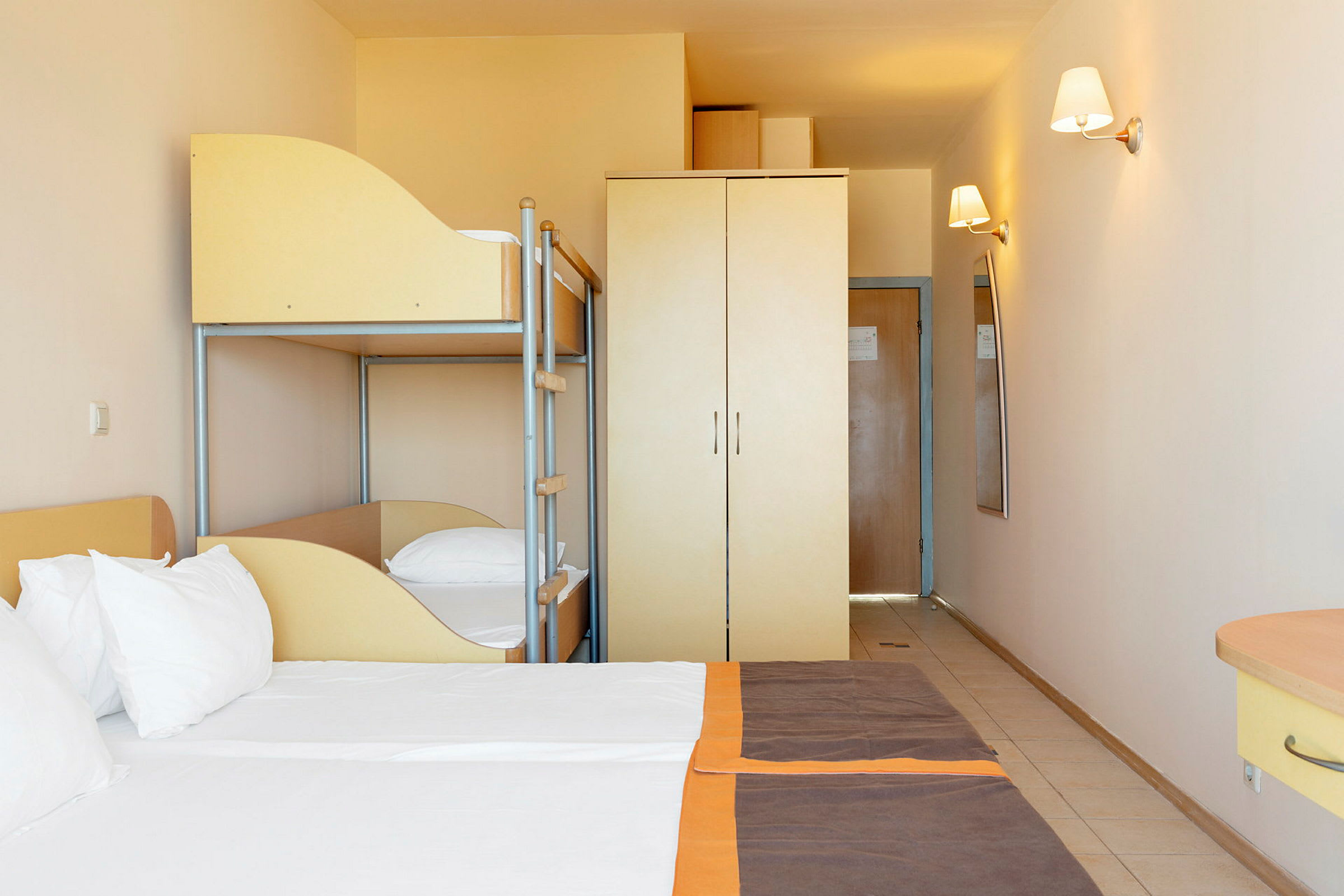 Hotelværelse med dobbeltseng, køjeseng og garderobe. (AI-genereret tekst)