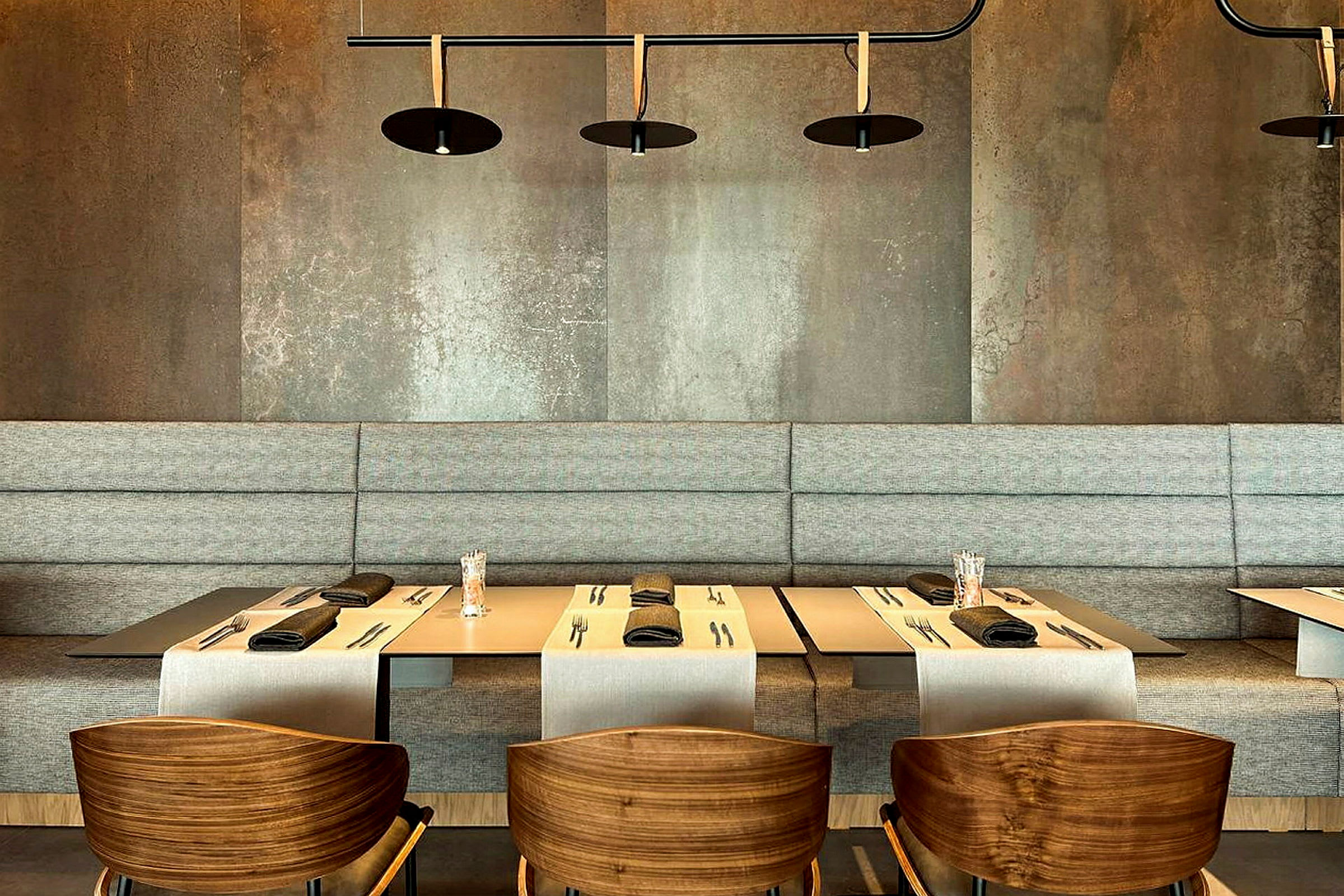 En moderne restaurantindretning med borde dækket til middag, stole med træsæder og en grå baggrund. (AI-genereret tekst)