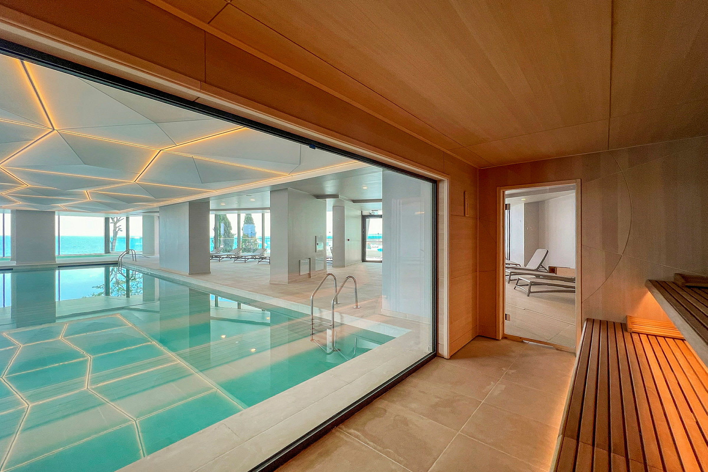 Interiør med en indendørs pool, store vinduer og en sauna med træinteriør. (AI-genereret tekst)