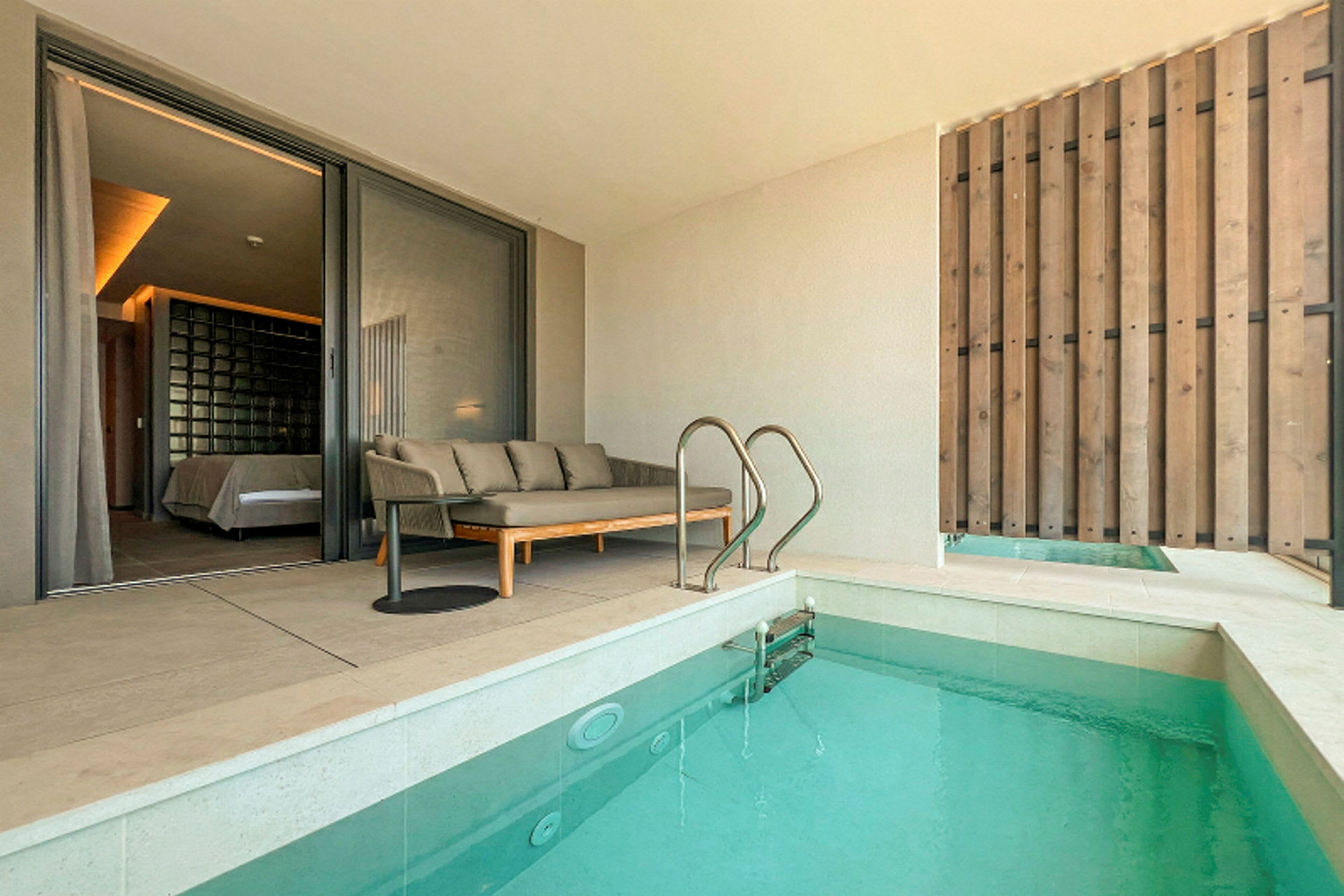 En terrasse med en sofa, et bord og en pool. (AI-genereret tekst)