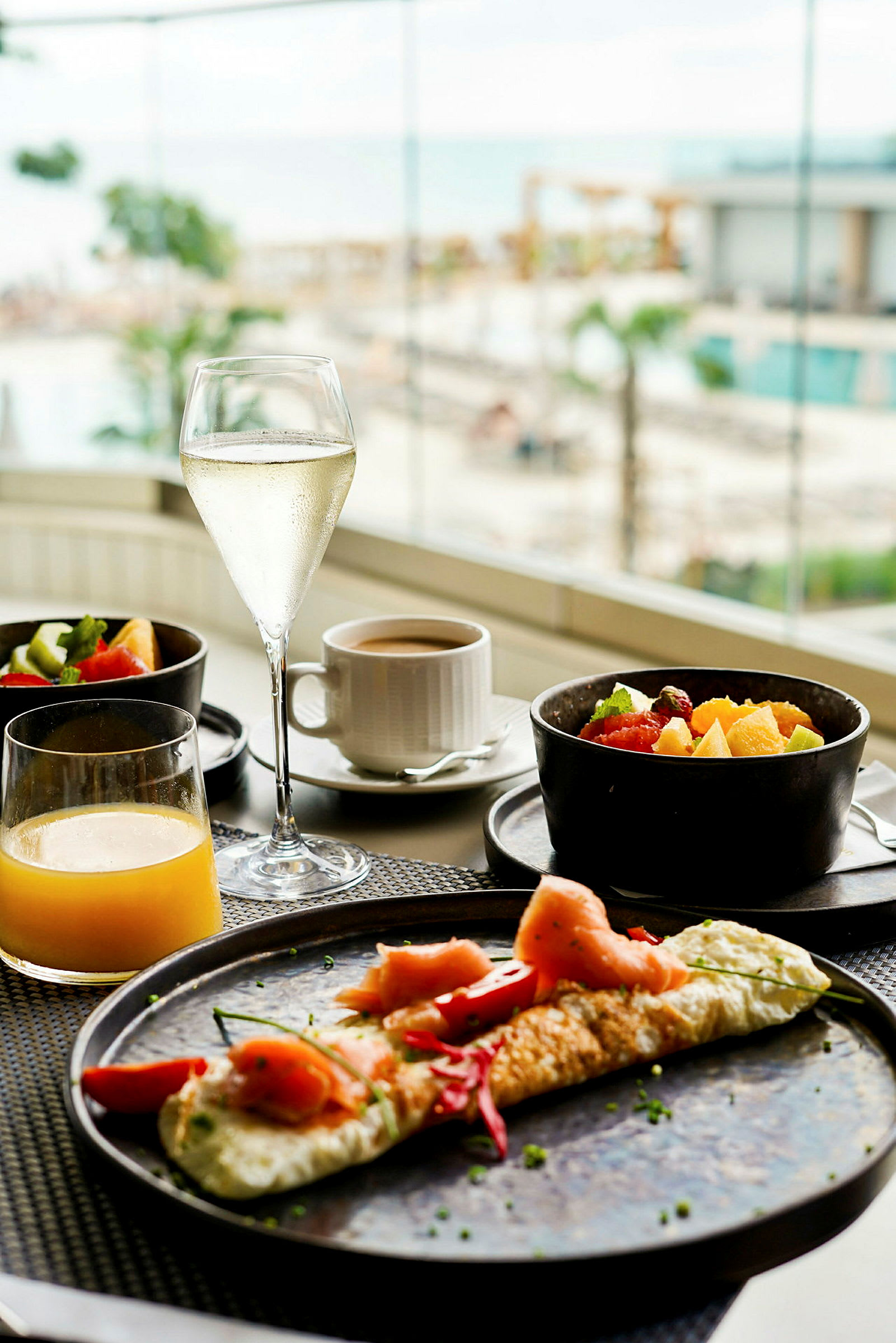 Morgenmad med omelet, friske frugter og drikke, med udsigt til en pool og havet. (AI-genereret tekst)