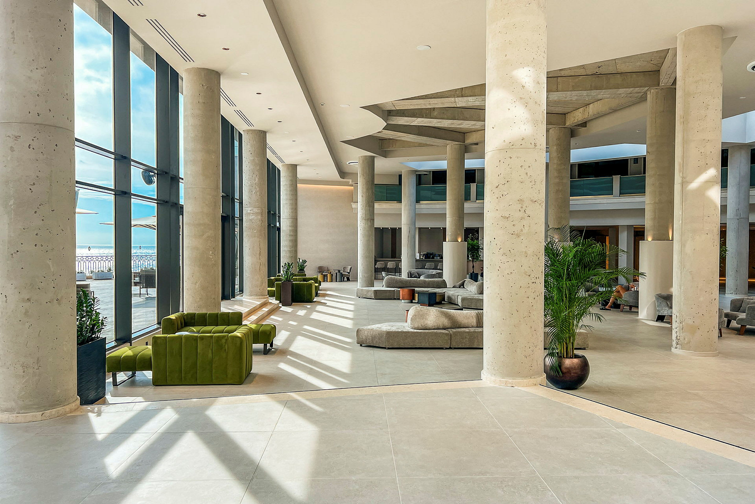 Hotellets moderne lobby med store vinduer og siddeområder. (AI-genereret tekst)