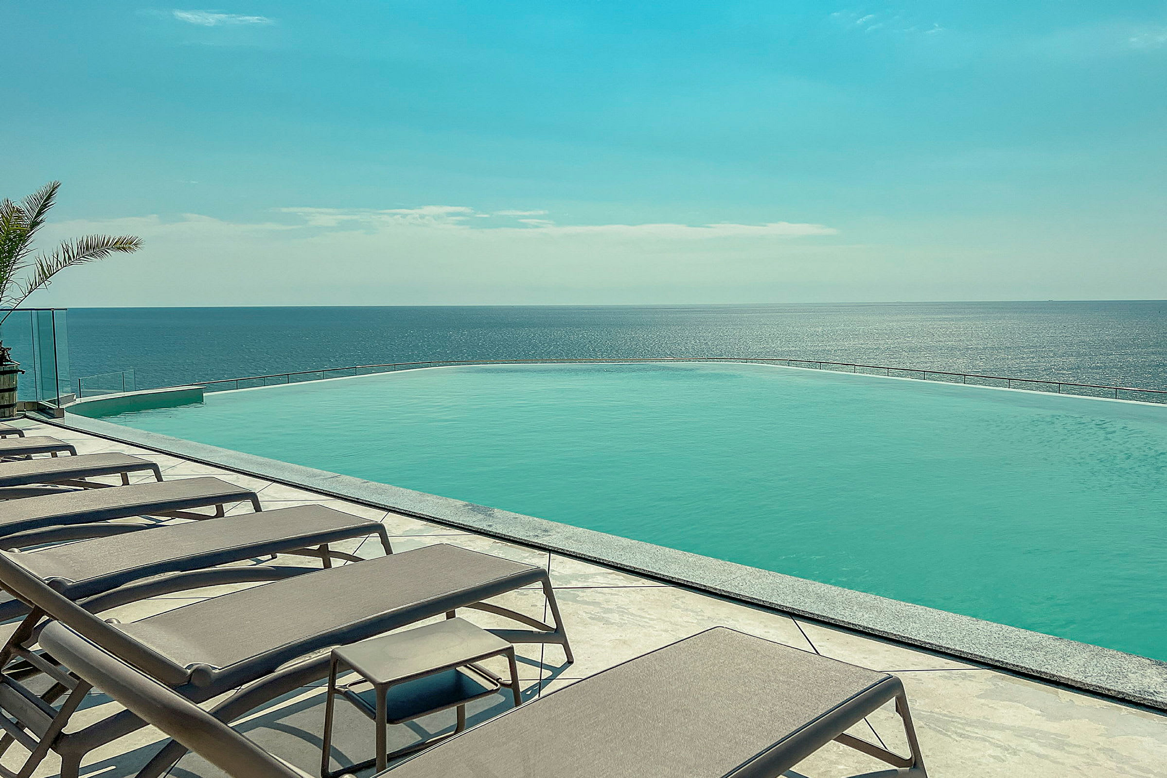 Liggestole ved en infinitypool med udsigt over havet. (AI-genereret tekst)