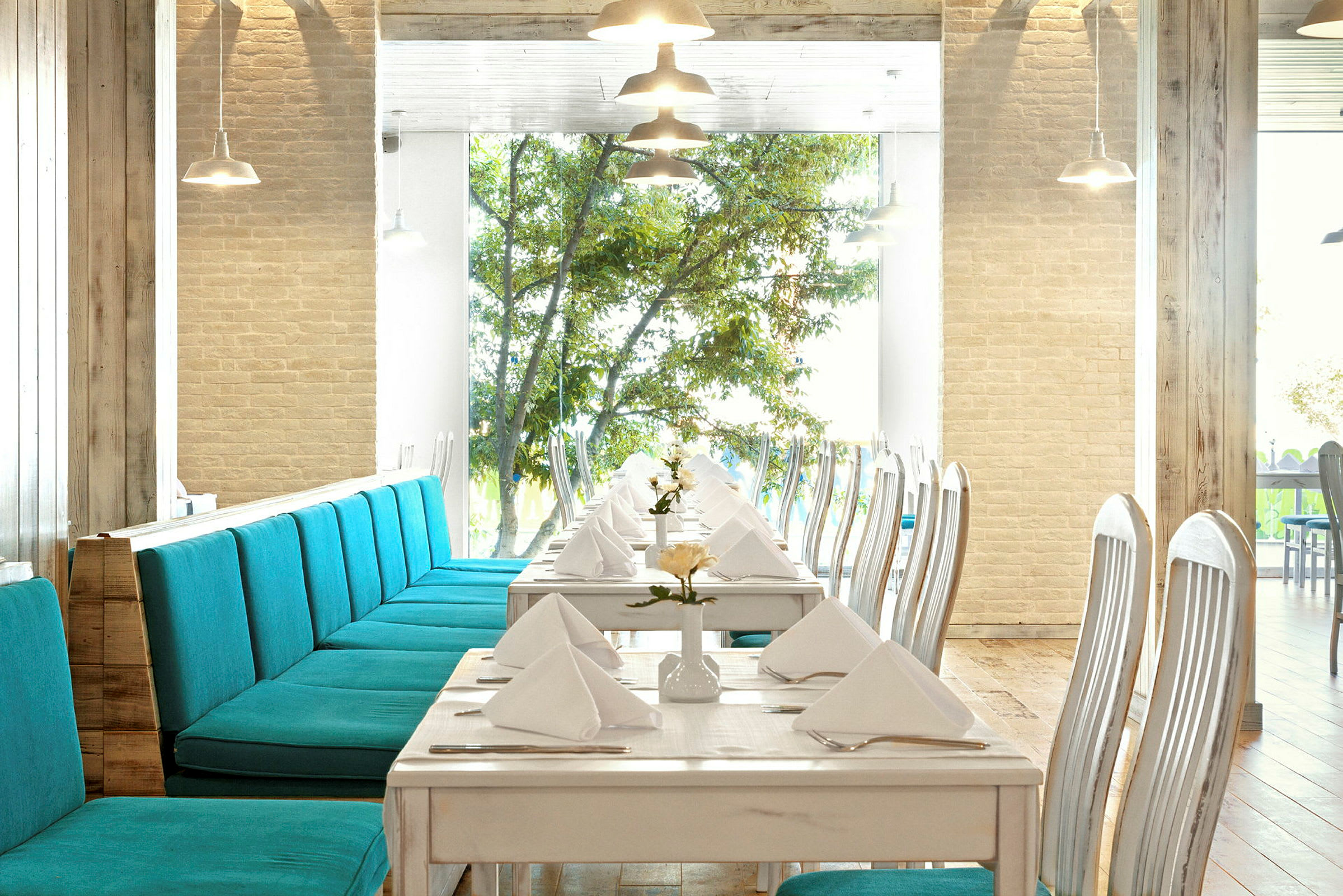 Restaurant med dækkede borde og turkise sofaer. (AI-genereret tekst)