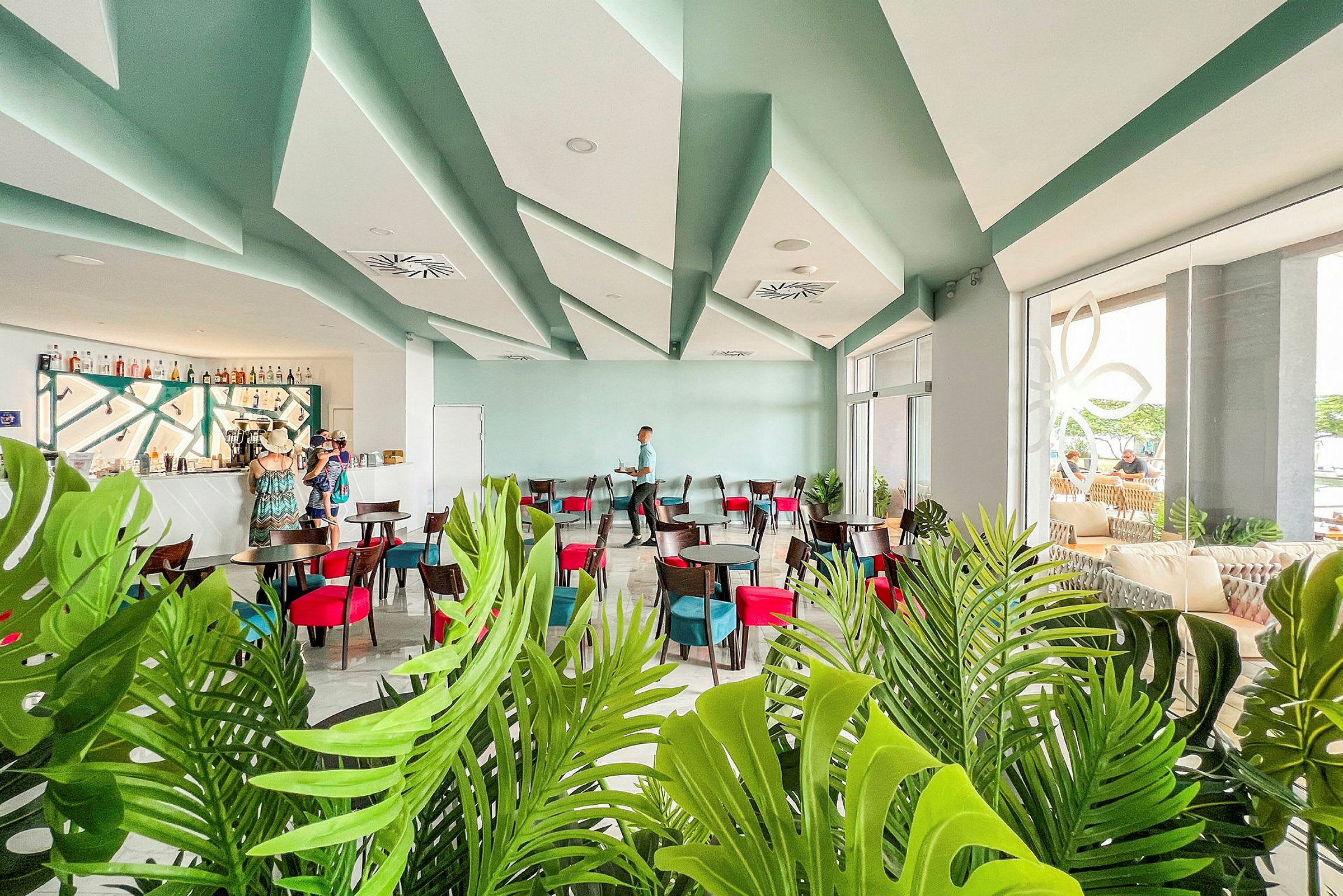 Moderne caféinteriør med siddegrupper og barområde, dekoreret med grønne planter. (AI-genereret tekst)