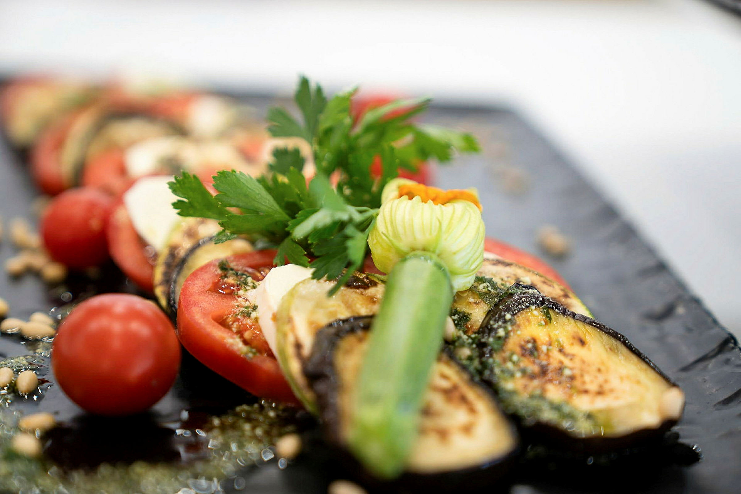 En tallerken med grillet aubergine, tomater og friske krydderurter. (AI-genereret tekst)