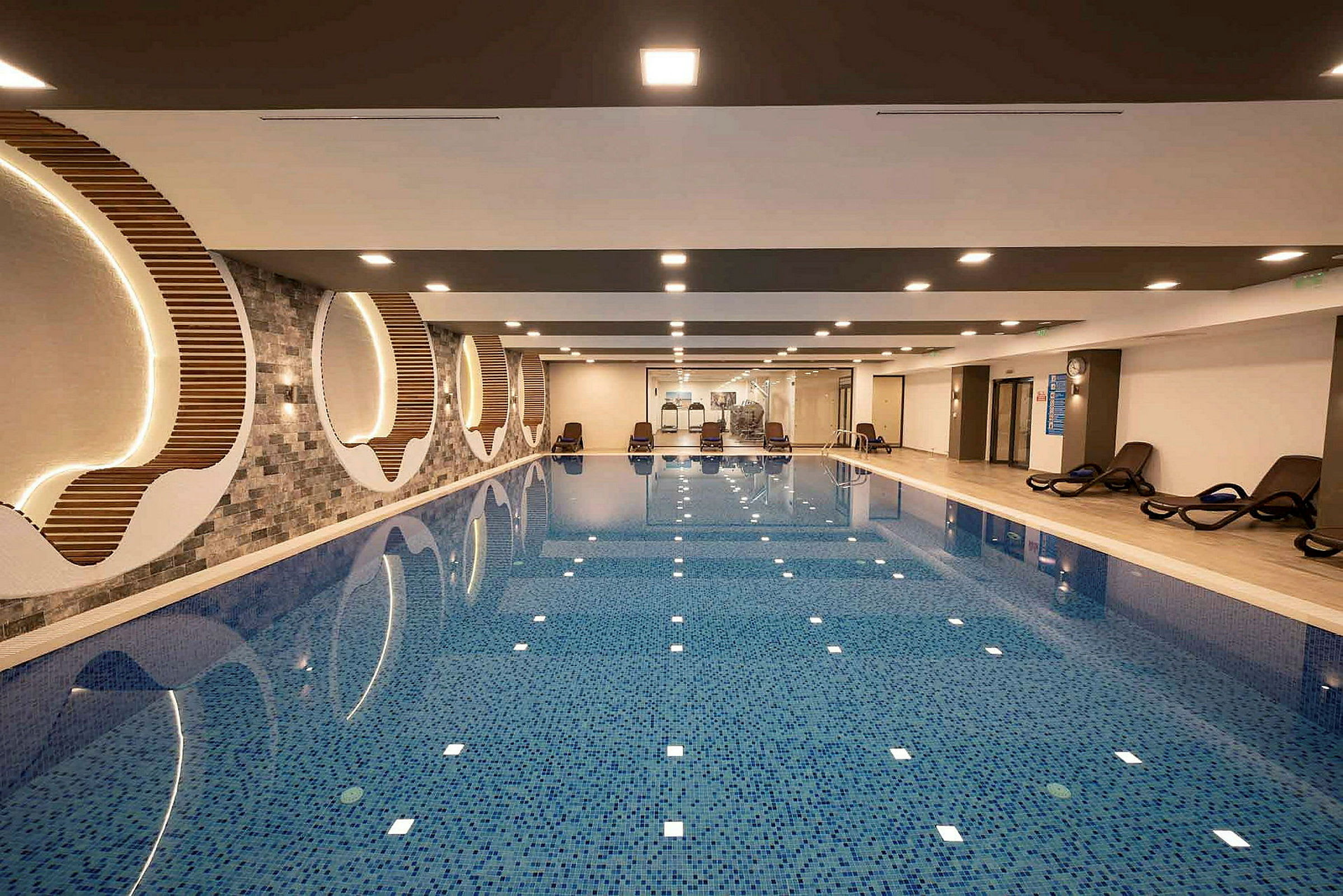 Indendørs pool med liggestole og moderne dekoration. (AI-genereret tekst)