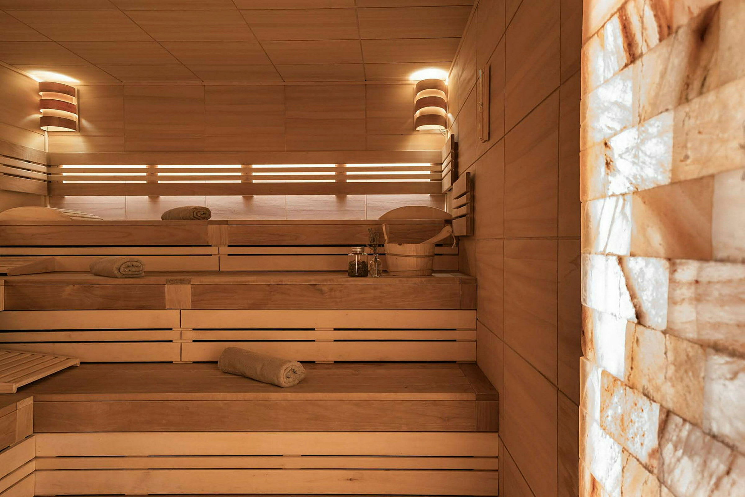 En sauna med træinteriør, flere siddebænke og håndklæder placeret på bænkene. (AI-genereret tekst)